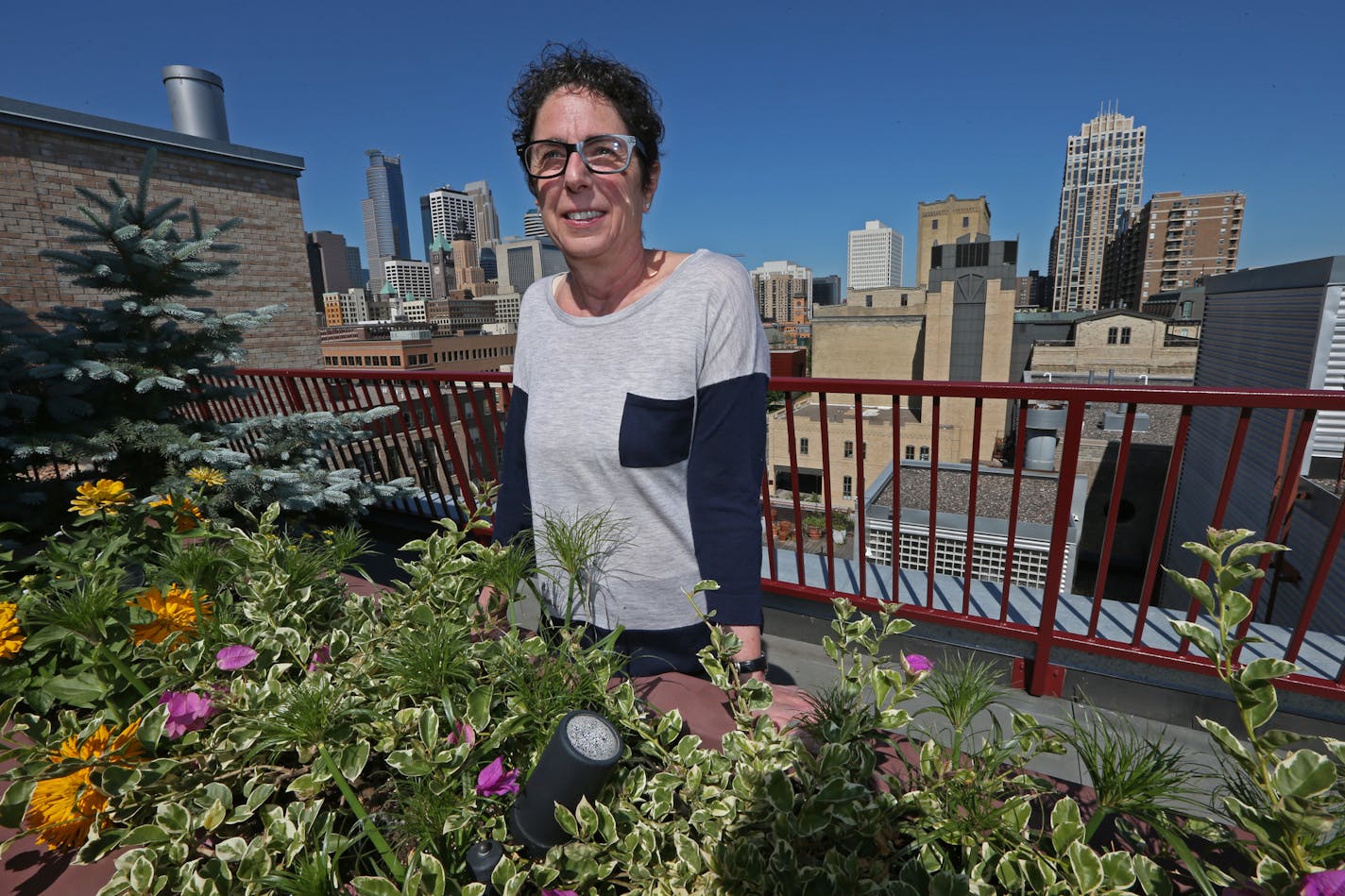 Marjorie Weiser on her rooftop garden at the Stone Arch Lofts, photographed on 6/13/14. The condo boom is producing a bumper crop of balcony and rooftop gardens, tended by everyone from empty nesters who downsized their garden along with their house, to young urbanites just learning how to grow.] Bruce Bisping/Star Tribune bbisping@startribune.com Marjorie Weiser/source.