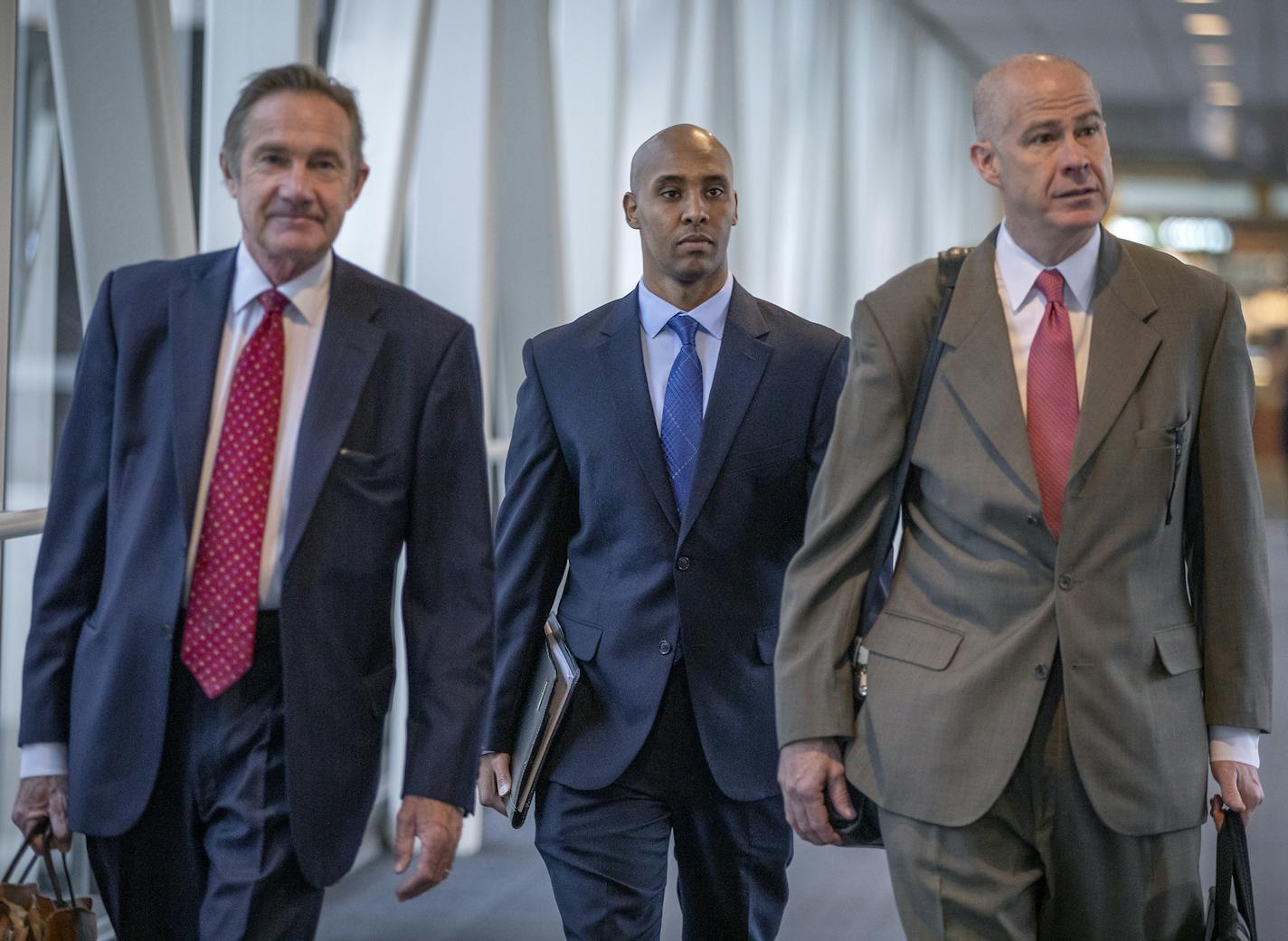 Flanked by his lawyers, Peter Wold, left, and Thomas Plunkett, right, former Minneapolis police officer Mohamed Noor made his way into court as testimony continues in the murder trial in the fatal shooting of Justine Damond .