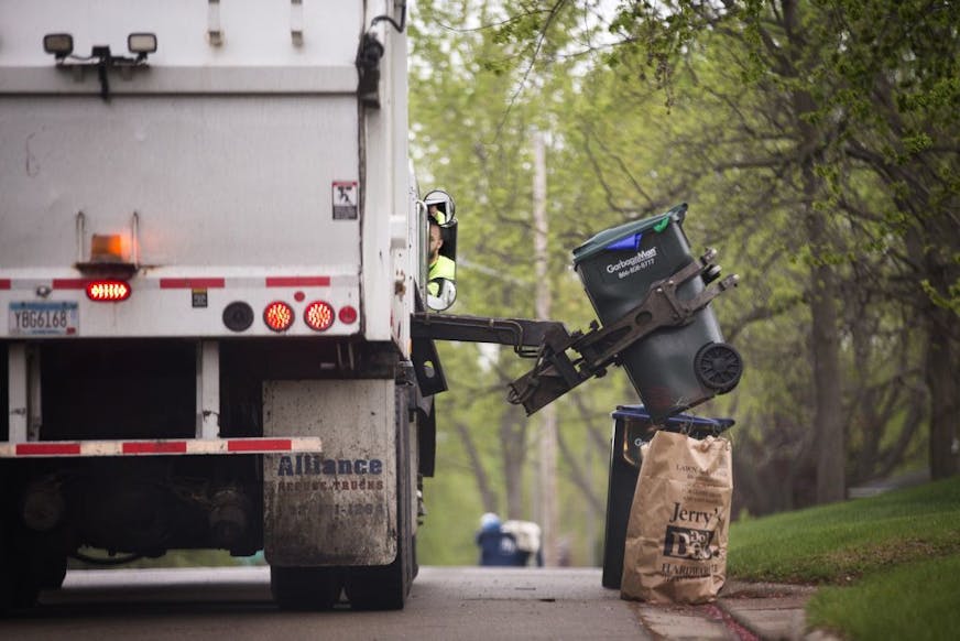 A GarbageMan worker empties containers onto the truck on trash pickup day in Bloomington between France Avenue and Normandale Boulevard on Thursday, May 7, 2015.