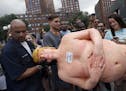 An employee of the New York City Department of Parks & Recreation removes a statue of a naked Republican presidential candidate Donald Trump, Thursday