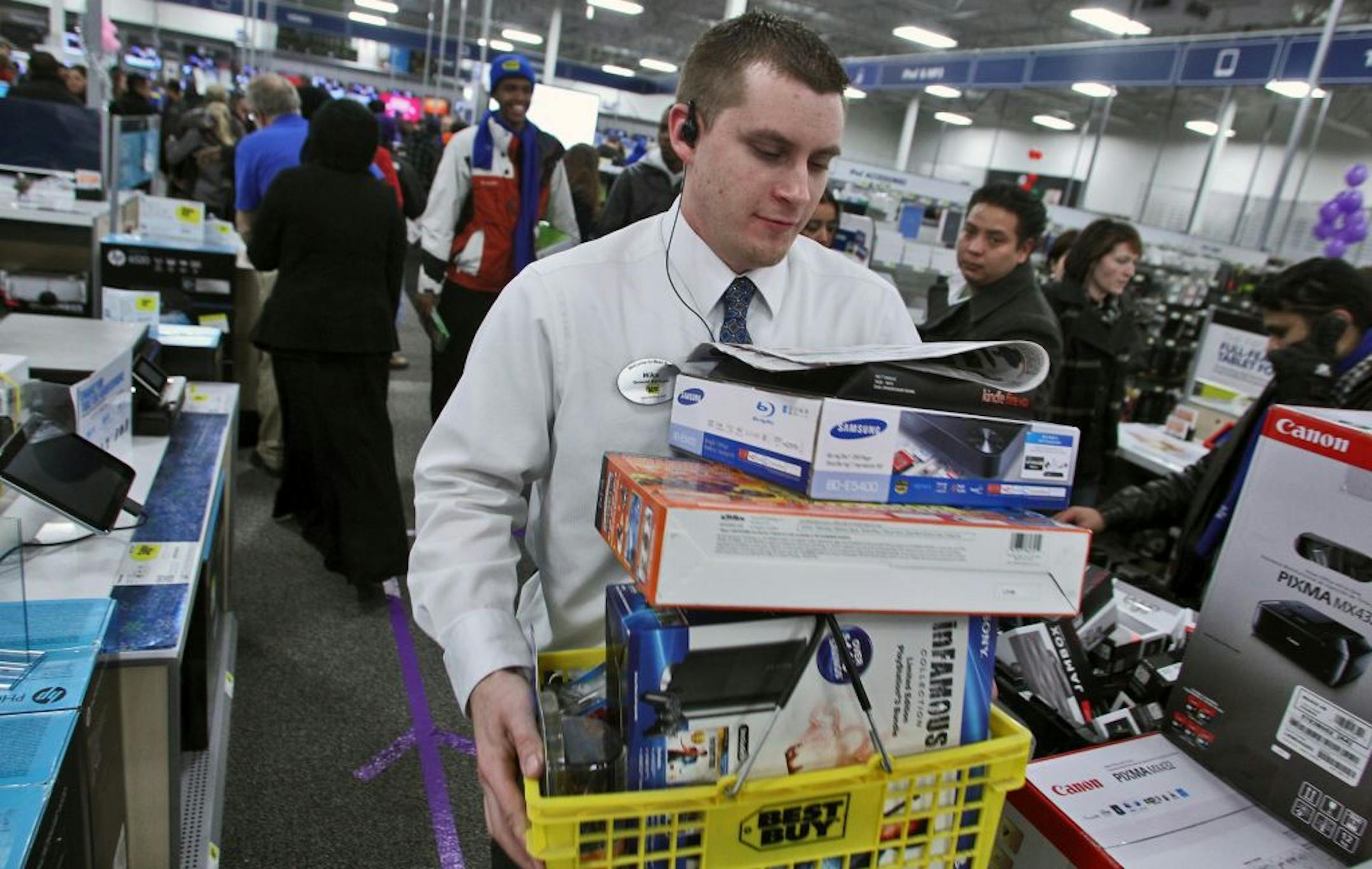 Mike Ersfeld, general manager of a Best Buy store in Eden Prairie, carried a customer's basket full of products to a checkout desk.