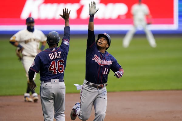 Minnesota Twins' Jorge Polanco celebrates his home run with third base coach Tony Diaz during the first inning of a baseball game against the Milwauke