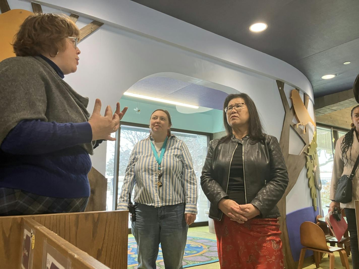 Kaohly Her stands with hands clasped as Maureen Hartman speaks and gestures.