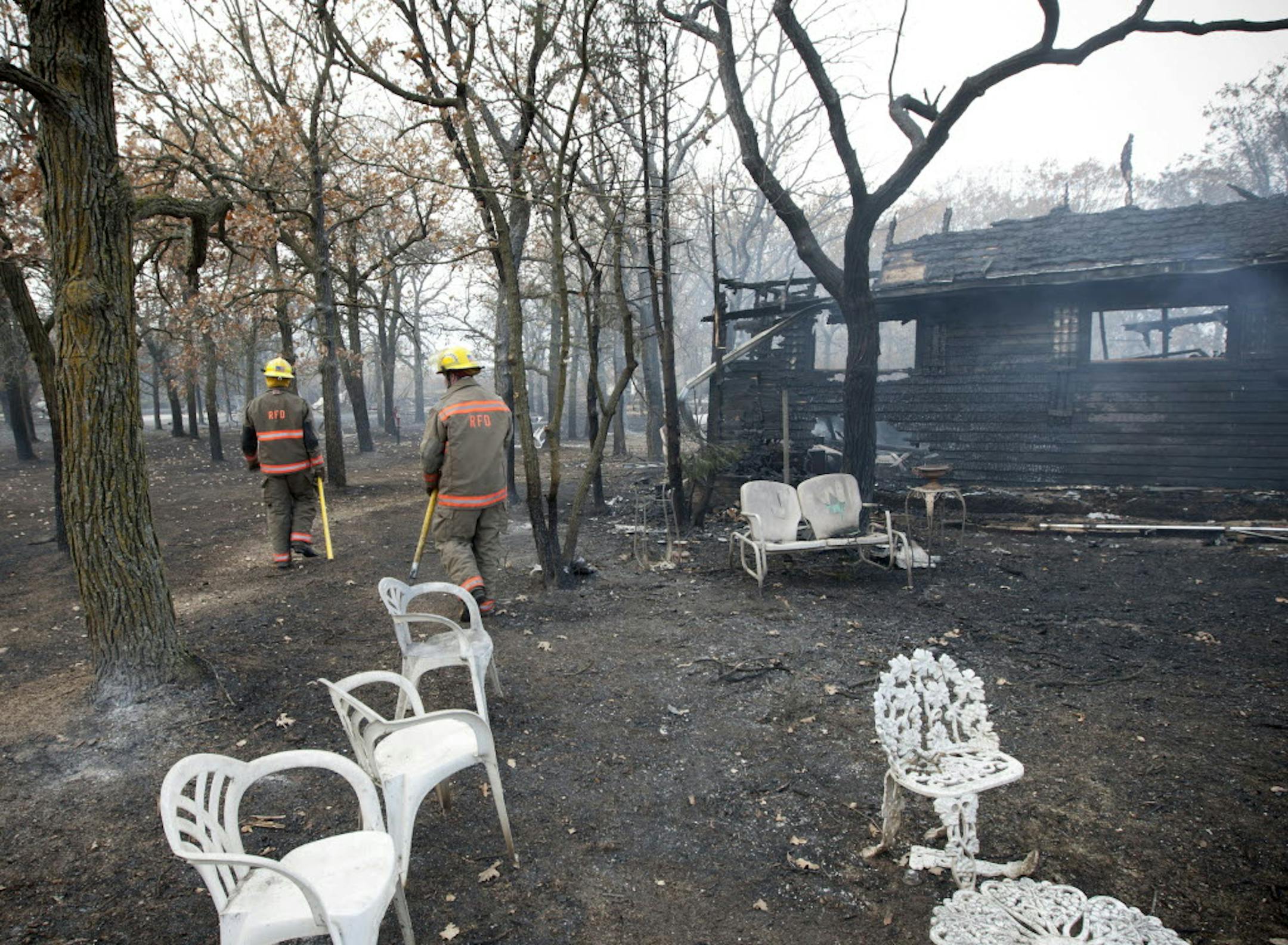 Roseau firefighters Kyle Peterson and Seth Novotny look for hot spots at the scene of one of several homes lost in Tuesday's wildfires at Karlstad, Minn.