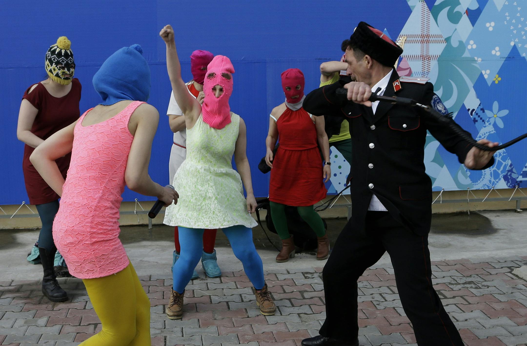 Members of the punk group Pussy Riot, including Nadezhda Tolokonnikova in the blue balaclava and Maria Alekhina in the pink balaclava, are attacked by Cossack militia in Sochi, Russia, on Wednesday, Feb. 19, 2014. The group had gathered in a downtown Sochi restaurant, about 30km (21miles) from where the Winter Olympics are being held. They ran out of the restaurant wearing brightly colored clothes and ski masks and were set upon by about a dozen Cossacks, who are used by police authorities in Ru
