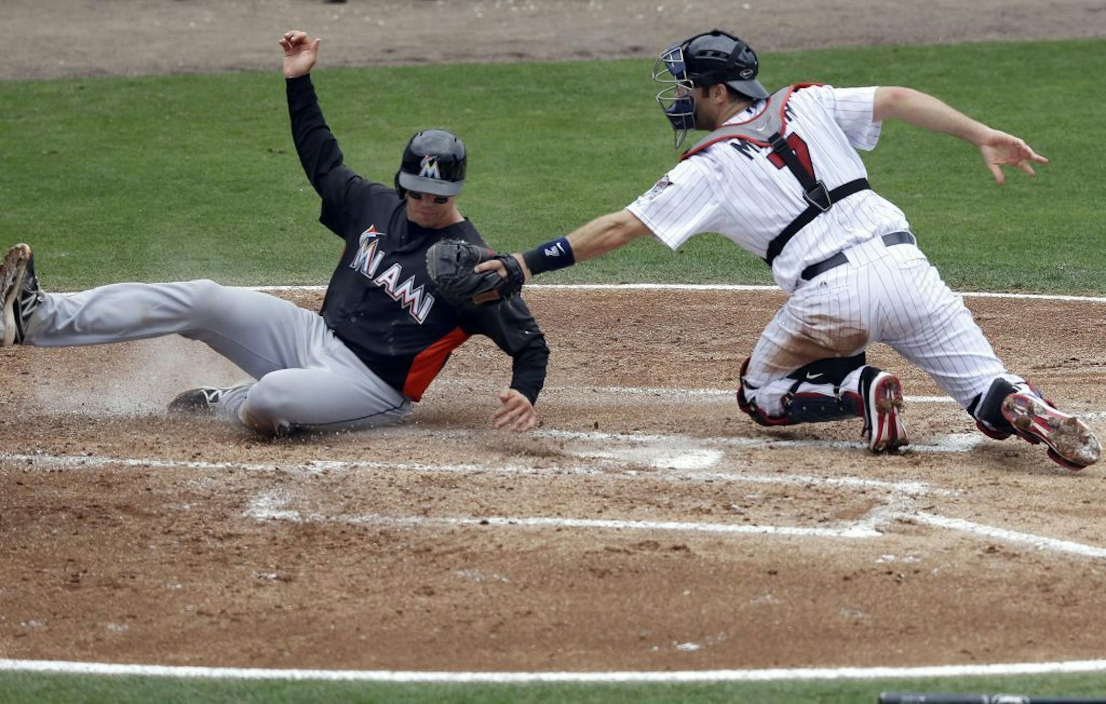 Miami Marlins' Kyle Skipworth is tagged out at the plate by Minnesota Twins catcher Joe Mauer on the back end of a double play on a grounder by Marlins' Chone Figgins in the second inning of an exhibition spring training baseball game in Fort Myers, Fla., Monday, March 18, 2013. The Marlins won 6-2.