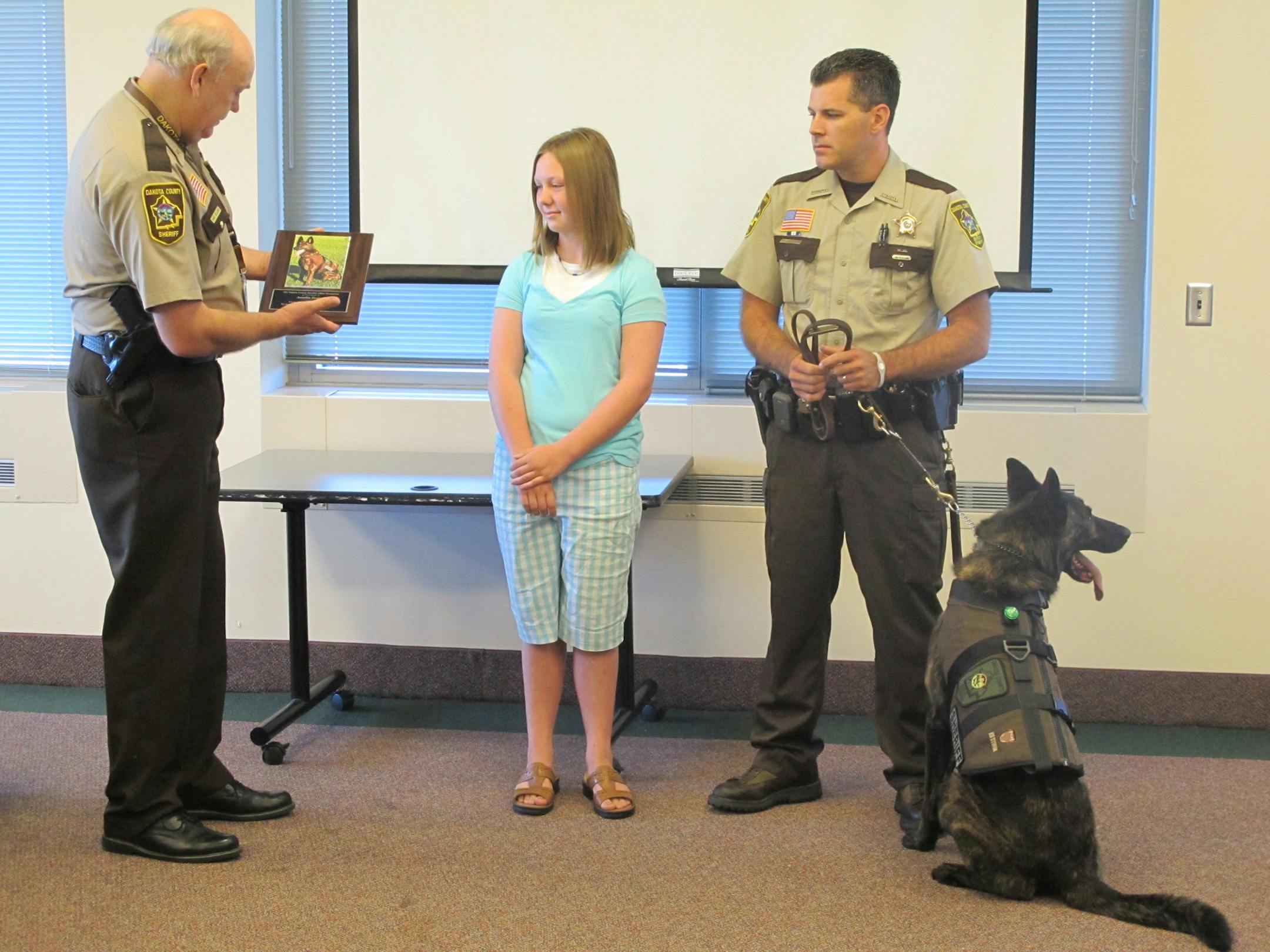 Some cutline info: Photo by Katie Humphrey Sheriff Dave Bellows presents a plaque to Amelia Foster, 11, to thank her for raising $1,955 to buy a protective vest for Ace, a K-9 who works with Dakota County Deputy Matt Schuster.