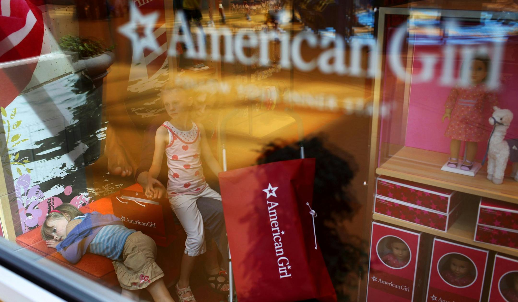 Anthony Souffle ¥ anthony.souffle@startribune.com Bloomington, Minn - June 27, 2009 - ] Caroline Olson, left, 5, lays on a bench in the American Girl store as her mom, Laurie, talks wtih her older sister, Madeline, 6, Saturday afternoon at the Mall of America in Bloomington.