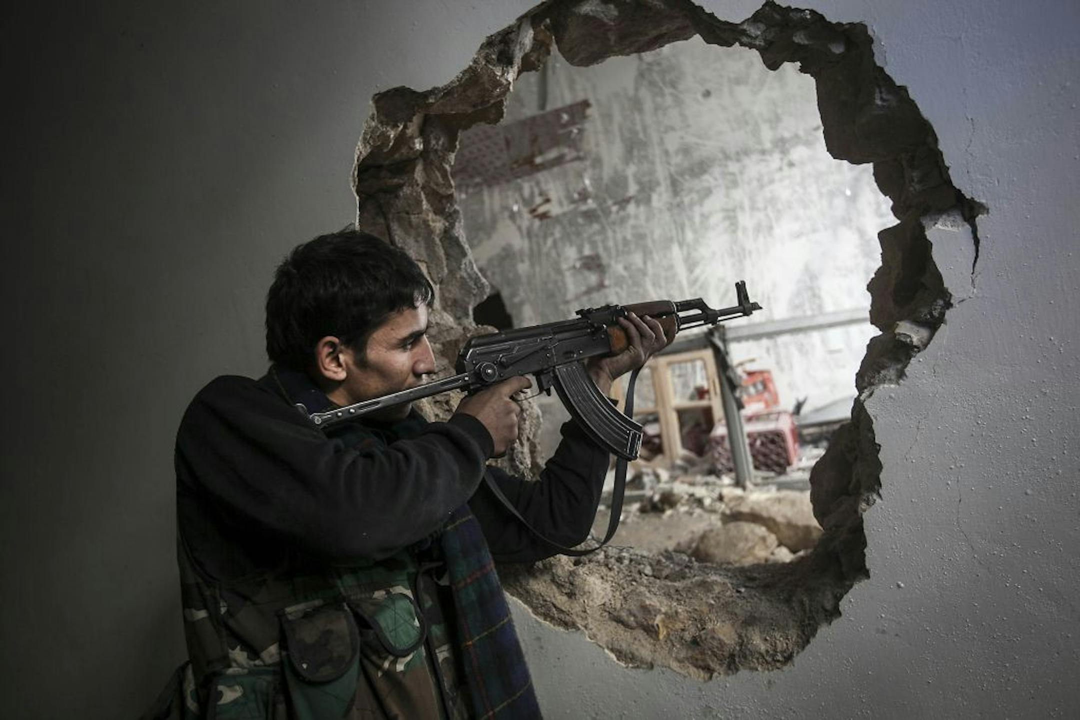 In this Sunday, Dec. 2, 2012 photo, a Free Syrian Army fighter aims his weapon during clashes with government forces in Aleppo, Syria.