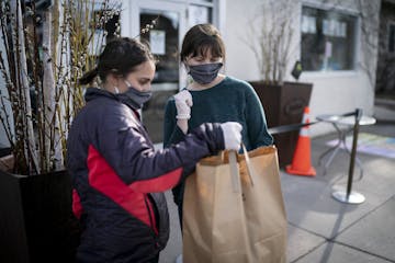 Diane Beck and Keelie Ritter looked up the car model at color on an order as they carried out meals to people's trunks at the Birchwood Cafe in Minnea