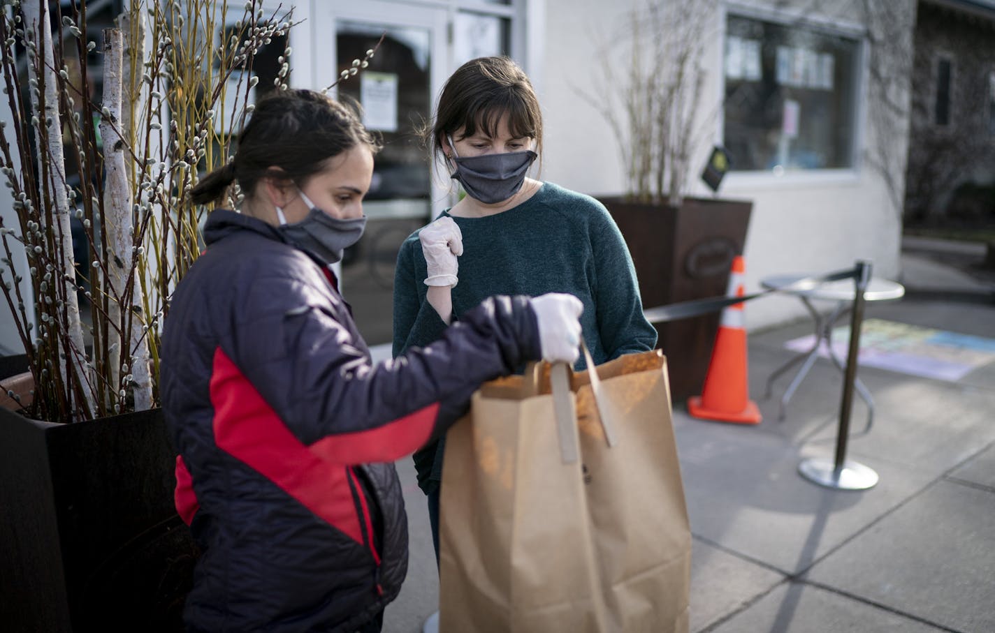 Diane Beck and Keelie Ritter looked up the car model at color on an order as they carried out meals to people's trunks at the Birchwood Cafe in Minneapolis, Minn., on Friday, April 10, 2020. Cars lined the street in front of the Birchwood Cafe as the restaurant sold out of it's Friday fish fry. ] RENEE JONES SCHNEIDER &#xa5; renee.jones@startribune.com