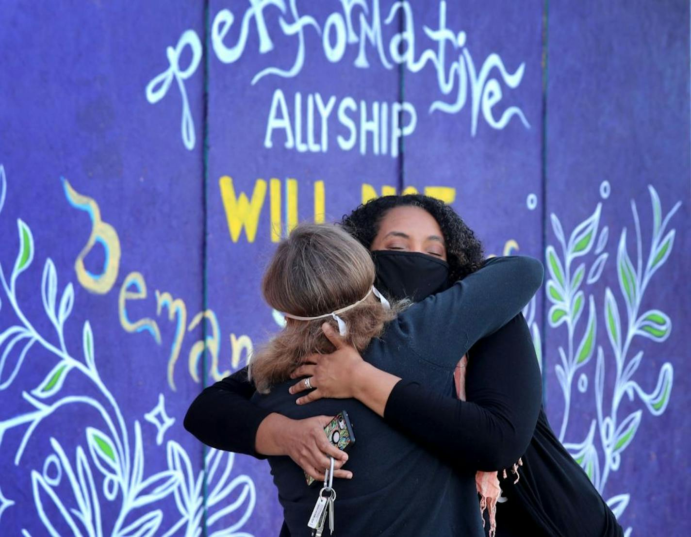 Crixell Shell, right, and Donna Minter, have joined forces through the Minnesota Peacebuilding Leadership Institute and were hugged after not seeing one another since mid-March near murals outside Steward Community Co-op Thursday in Minneapolis. Minter is a neuropsychologist and forensic psychologist who is licensed to help professionals understand racial trauma in the context of history, community, institutions and natural disasters and is also the founder and co-executive director of Peacebuil