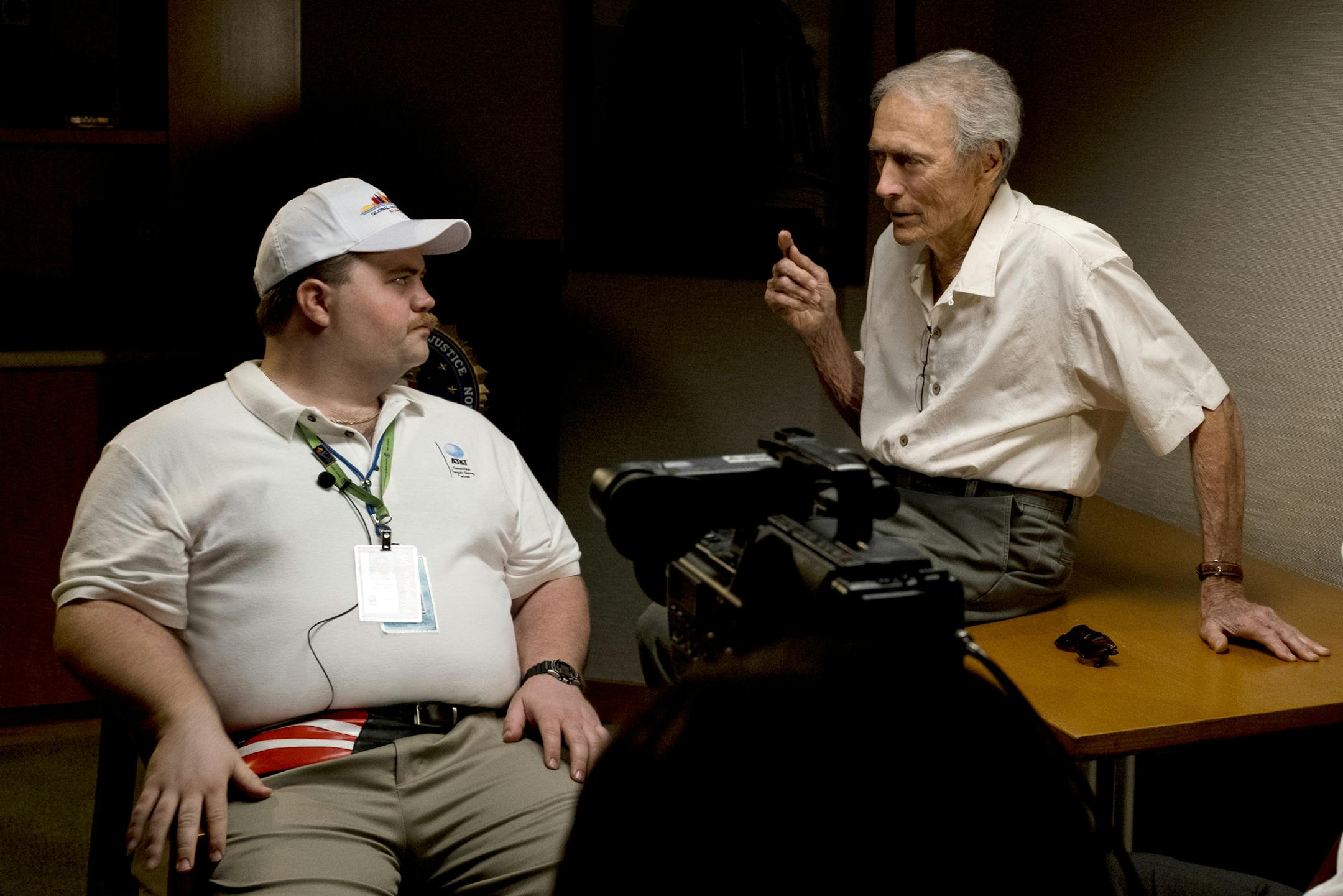 In this image released by Warner Bros. Pictures, director Clint Eastwood speaks with actor Paul Walter Hauser as they work during the filming of the movie "Richard Jewell." When a bomb exploded in a downtown Atlanta park midway through the 1996 Olympics, it set news reporters and law enforcement on a collision course that upended the life of a security guard, turning him from hero to villain overnight. Now, more than 20 years later, a recent book and upcoming movie explore Jewell's ordeal and th