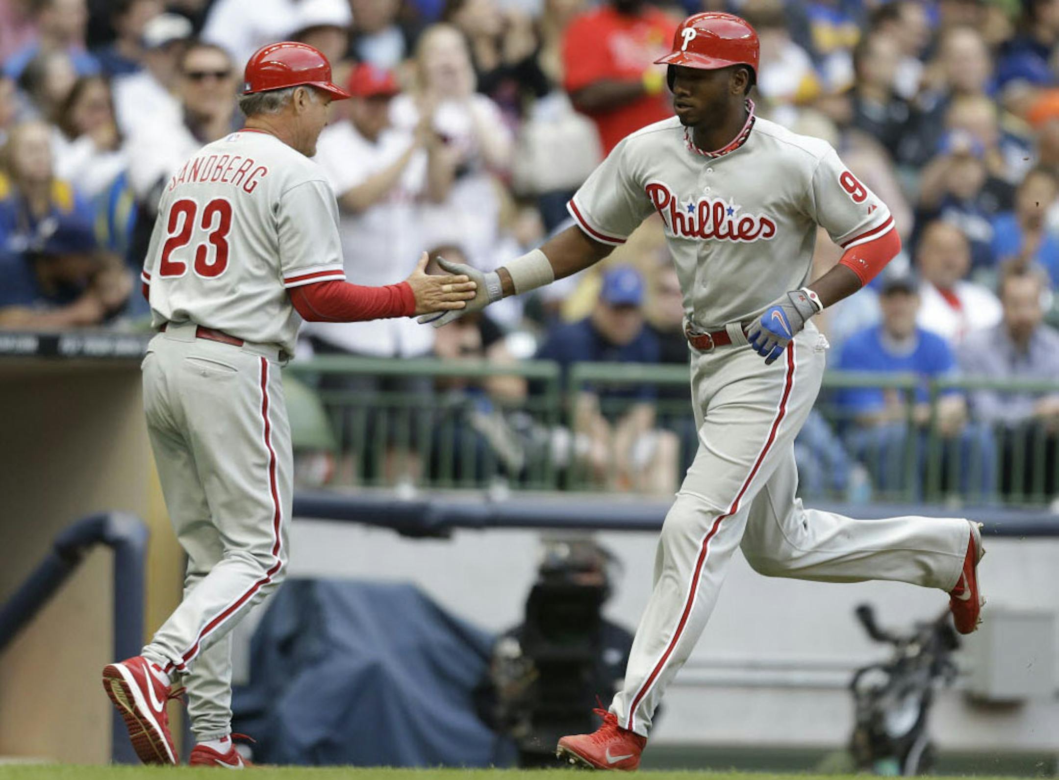Philadelphia's Domonic Brown, right, celebrates his home run with third base coach Ryne Sandberg, left, Saturday against the Milwaukee Brewers.