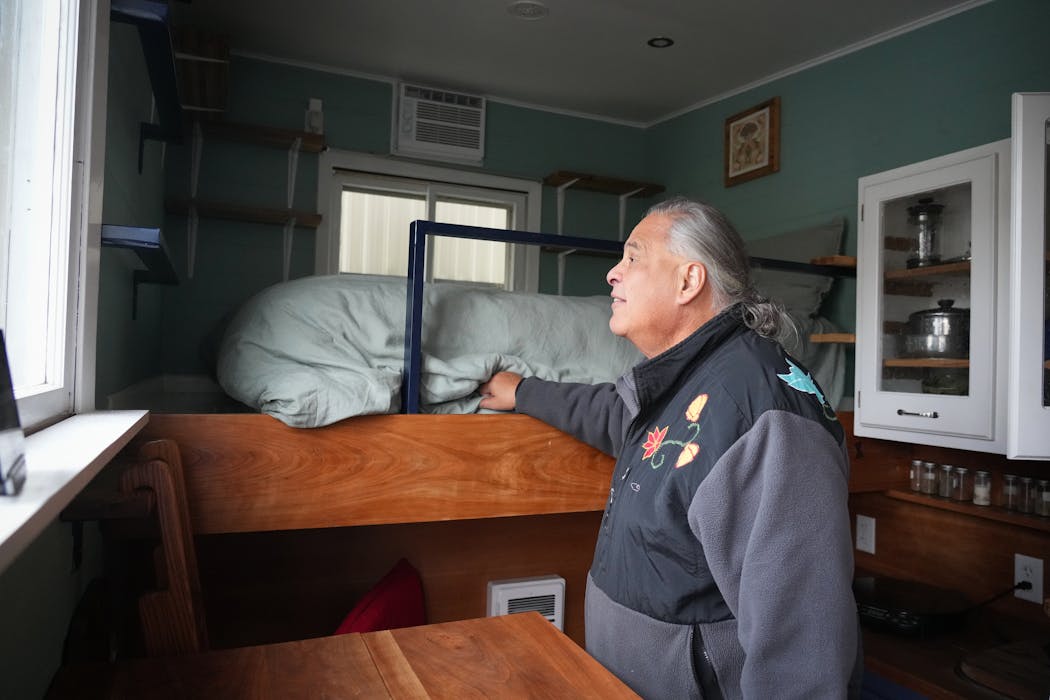 Michael Goze, chief executive of the American Indian Community Development Corporation, steps inside a tiny home trailer that was donated to his nonprofit and is sitting outside the Homeward Bound emergency shelter Friday.