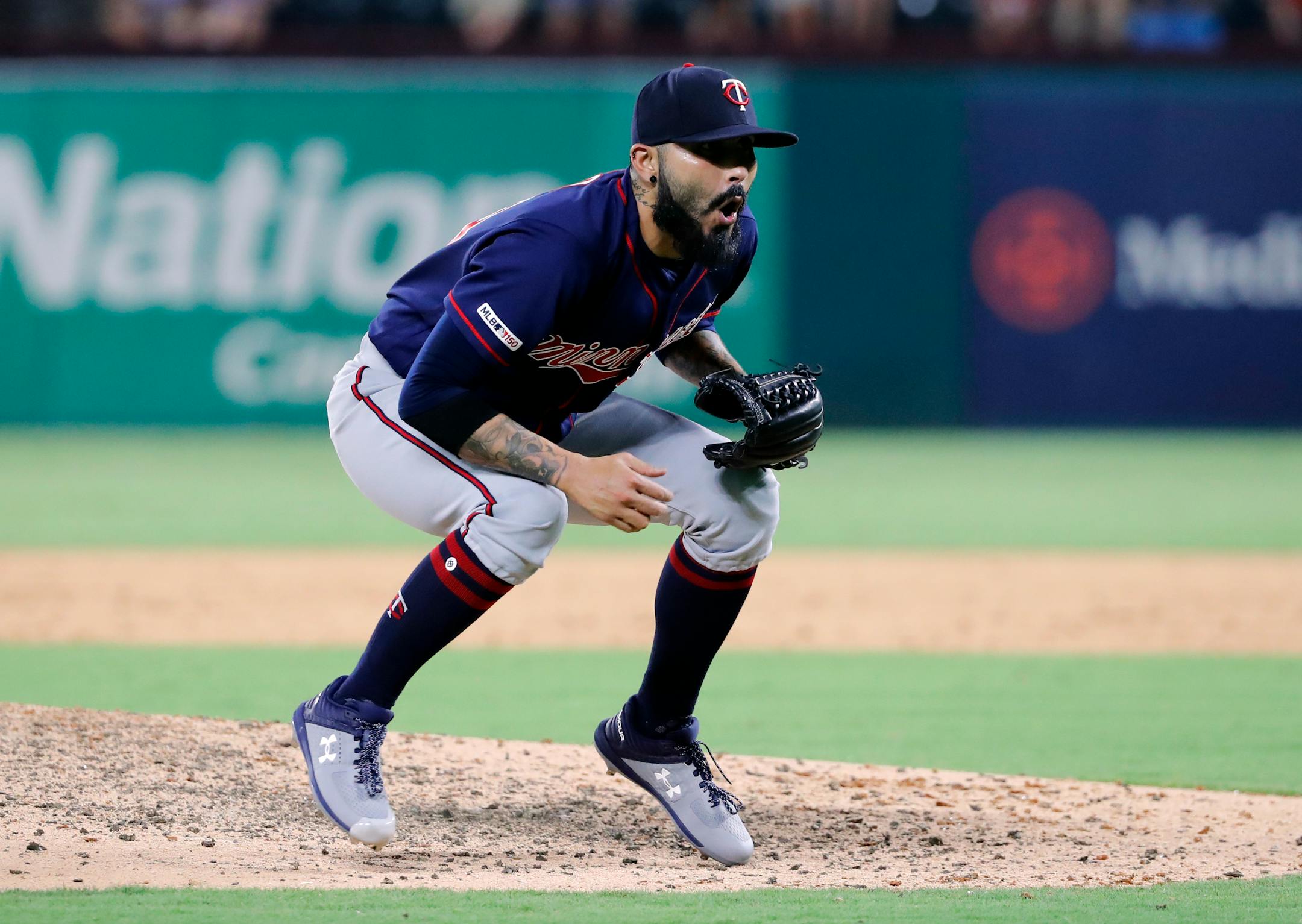 Minnesota Twins closer Sergio Romo crouches over at the front of the mound after walking Texas Rangers' Shin-Soo Choo during the ninth inning of a baseball game in Arlington, Texas, Friday, Aug. 16, 2019. (AP Photo/Tony Gutierrez)