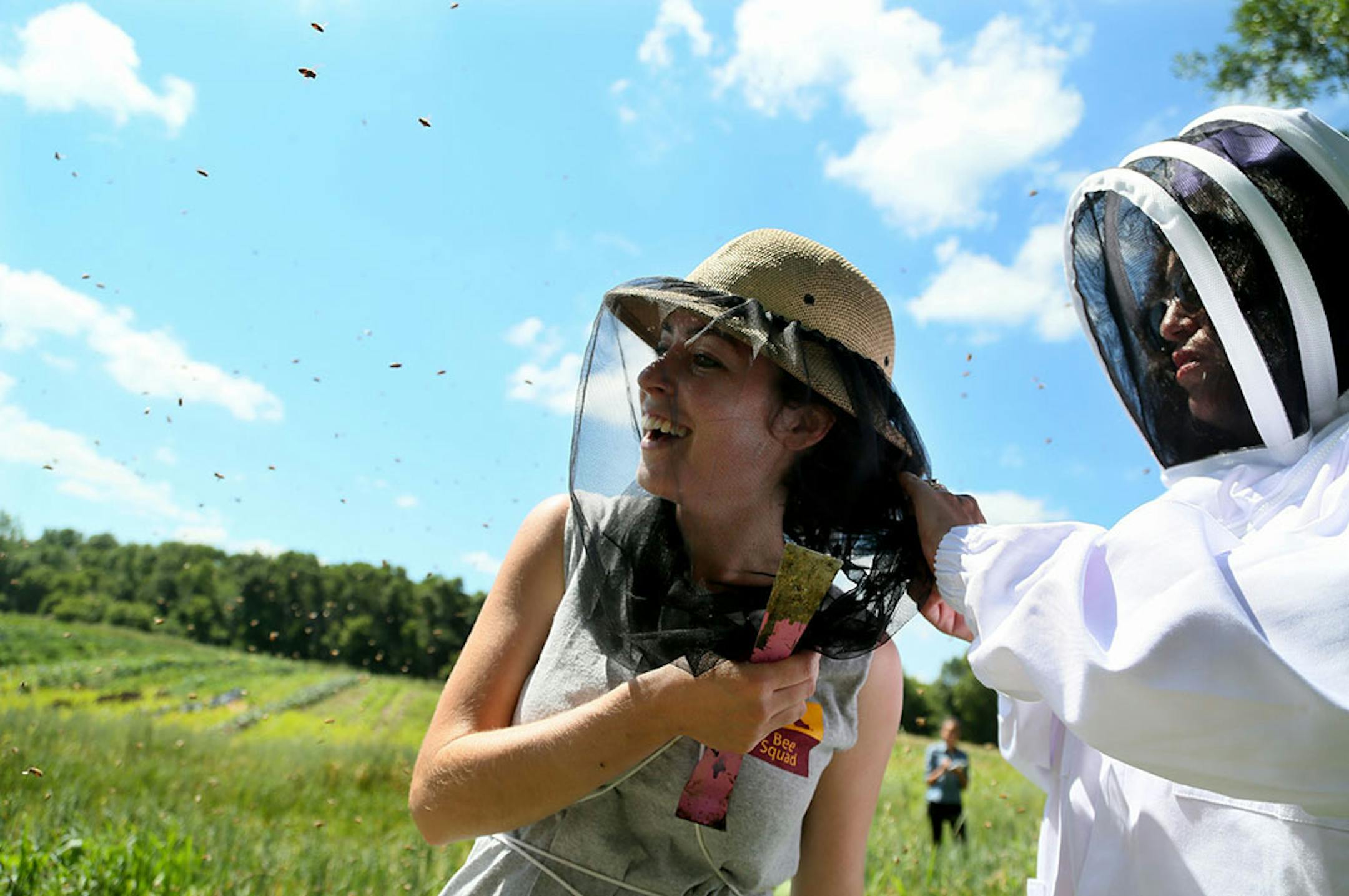 Reinas de Miel consists of five women and one youth who work at the hives every Thursday, including Thursday, July 23, 2015, at a farm in Lakeville, MN. Here, Bridget Mendel, University of Minnesota bee squad bee keeper and mentor to the group, gets an assist from Susana Espinosa de Sygulla, right, in getting a bee out of her hair that had managed to get underneath her netting. Urban Ventures has partnered with the University of Minnesota to train low-income women to become beekeepers.