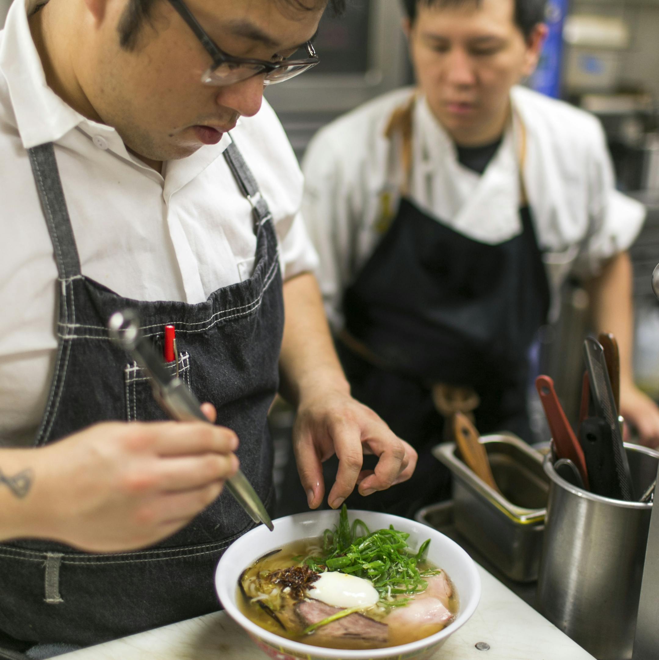 -- PHOTO MOVED IN ADVANCE AND NOT FOR USE - ONLINE OR IN PRINT - BEFORE NOV. 30, 2014. -- Andrew Le, chef and owner of The Pig and the Lady restaurant, right, looks on as noodle chef Chris Kimoto finishes a bowl of Vietnamese pho soup at the restaurant in Honolulu, Oct. 31, 2014. A recent wave of high-end chefs with impressive fine-dining pedigrees at restaurants in Honolulu have been taking inspiration from farmers’ markets and Hawaii’s Asian heritage, creating dishes that feature