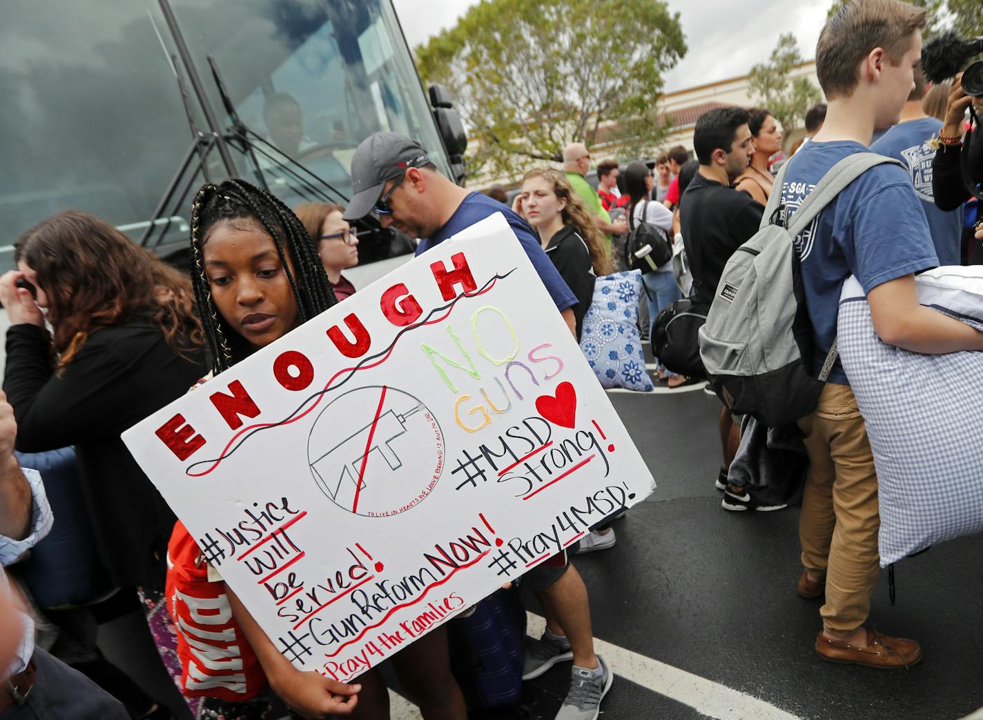 Tyra Hemans, 19, left, and Logan Locke, 17, right, students who survived the shooting at Stoneman Douglas High School, wait to board buses in Parkland, Fla., Tuesday, Feb. 20, 2018. The students plan to hold a rally Wednesday in hopes that it will put pressure on the state's Republican-controlled Legislature to consider a sweeping package of gun-control laws, something some GOP lawmakers said Monday they would consider. (AP Photo/Gerald Herbert)