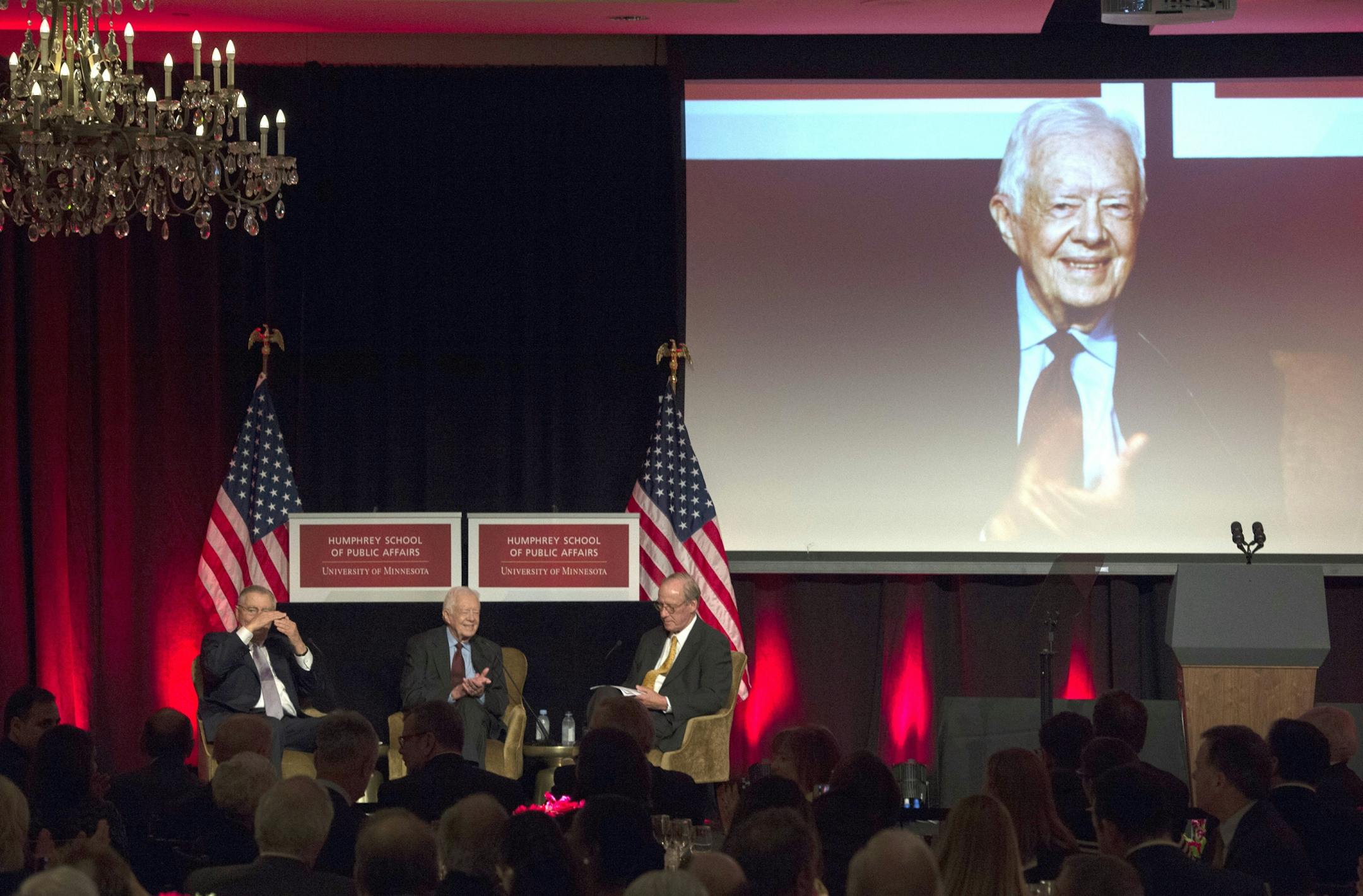 Former President Jimmy Carter, center takes part in a tribute of former Vice President Walter Mondale, left, and moderator Richard Moe, right, in Washington, Tuesday, Oct. 20, 2015.