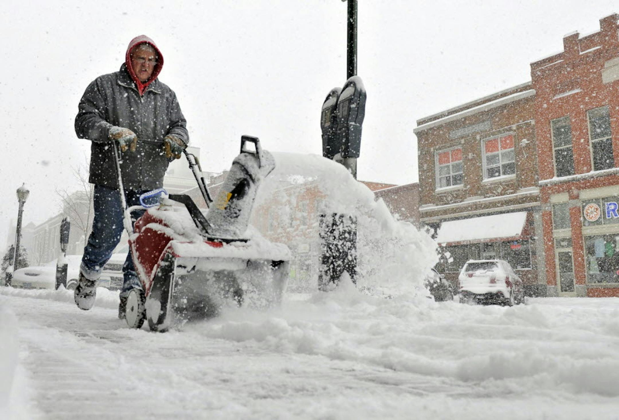 March 18, 2014: Dan Borgert clears sidewalks along storefronts a snow falls in St. Cloud, Minn.