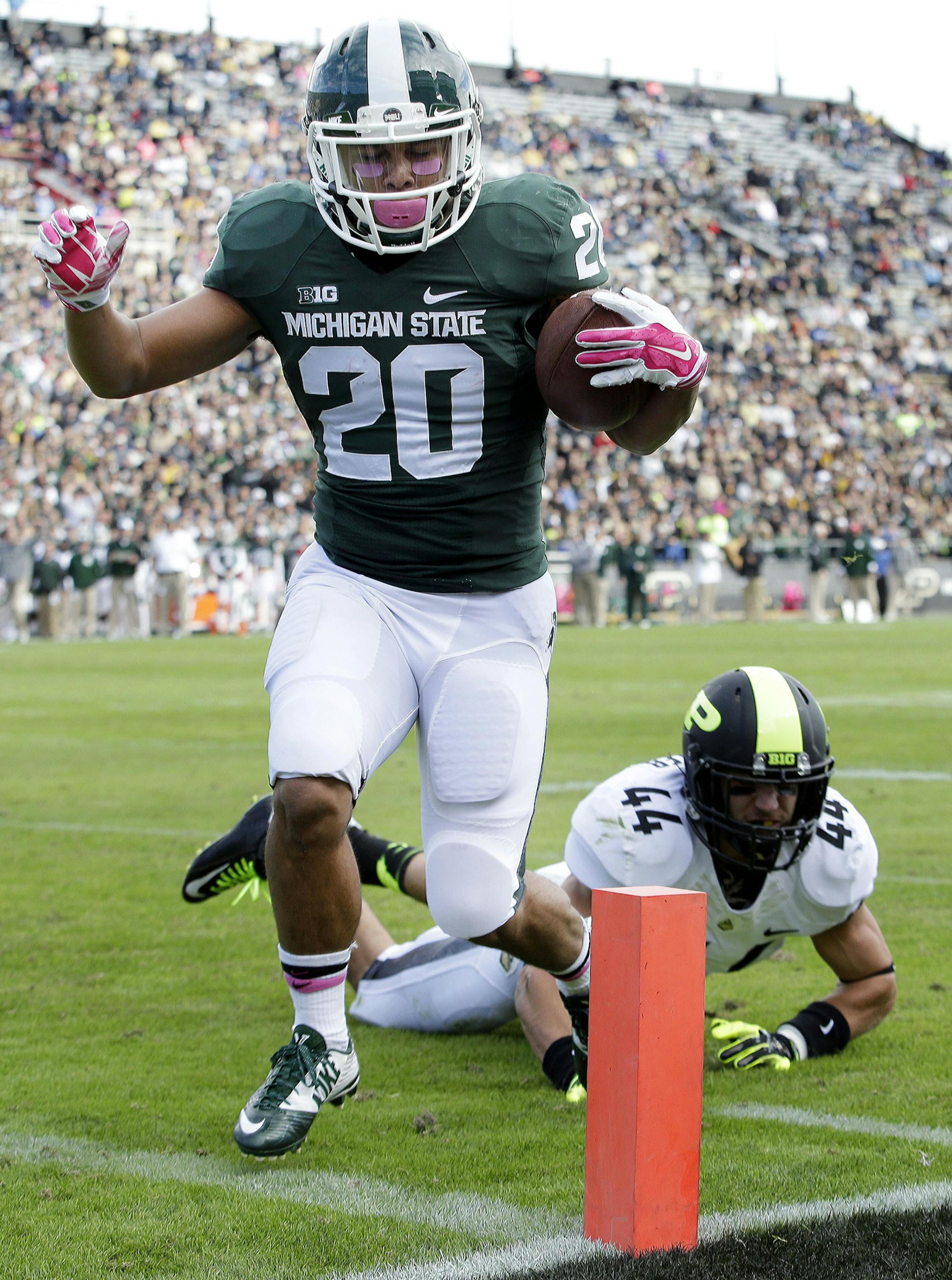 Michigan State running back Nick Hill (20) scores a touchdown in front of Purdue safety Landon Feichter (44) during the first quarter of an NCAA college football game in West Lafayette, Ind., Saturday, Oct. 11, 2014. (AP Photo/AJ Mast)