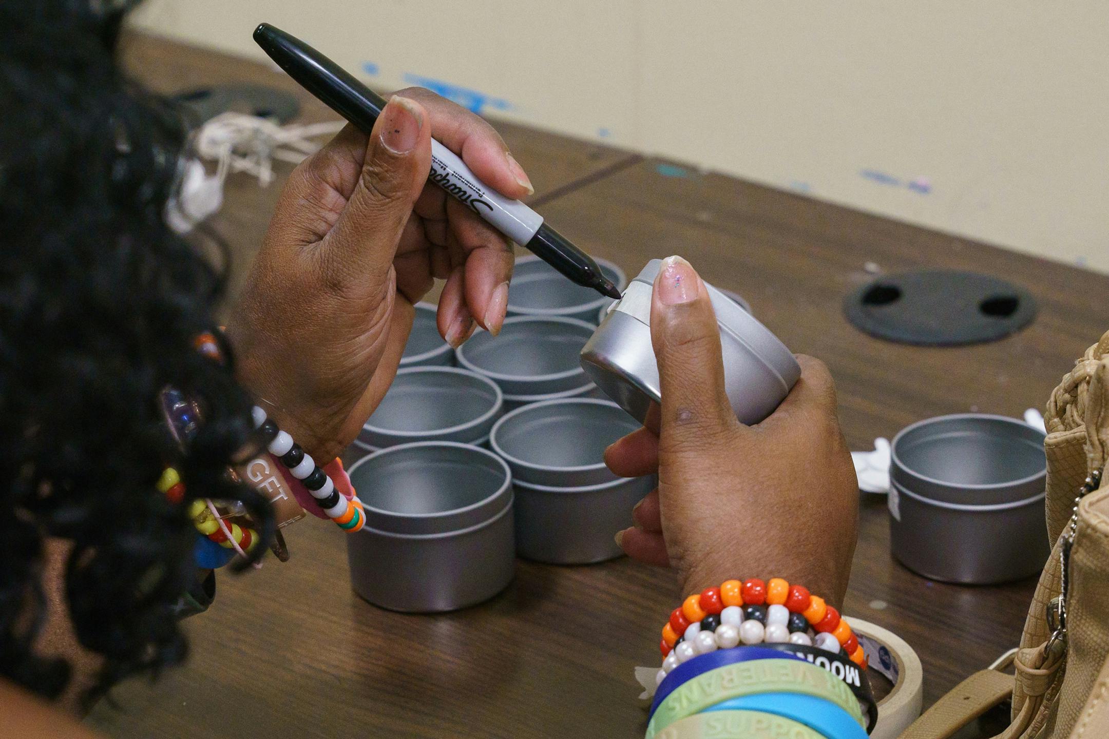 Linette Peden writes her name on candle containers as part of a gift box business that brings money into the Project Home organization on Aug. 28, 2019 in Philadelphia. (Jessica Griffin/The Philadelphia Inquirer/TNS) ORG XMIT: 1415266 ORG XMIT: MIN1909060338116783