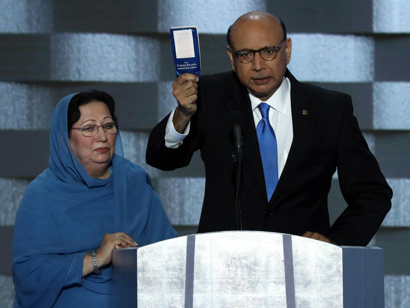 Khizr Khan, father of Army Capt. Humayun S. M. Khan, who died in fighting in Iraq, holds up his pocket copy the Constitution as he speaks, with his wife looking on, on the final day of the Democratic National Convention in Philadelphia, July 28, 2016. (Jim Wilson/The New York Times)