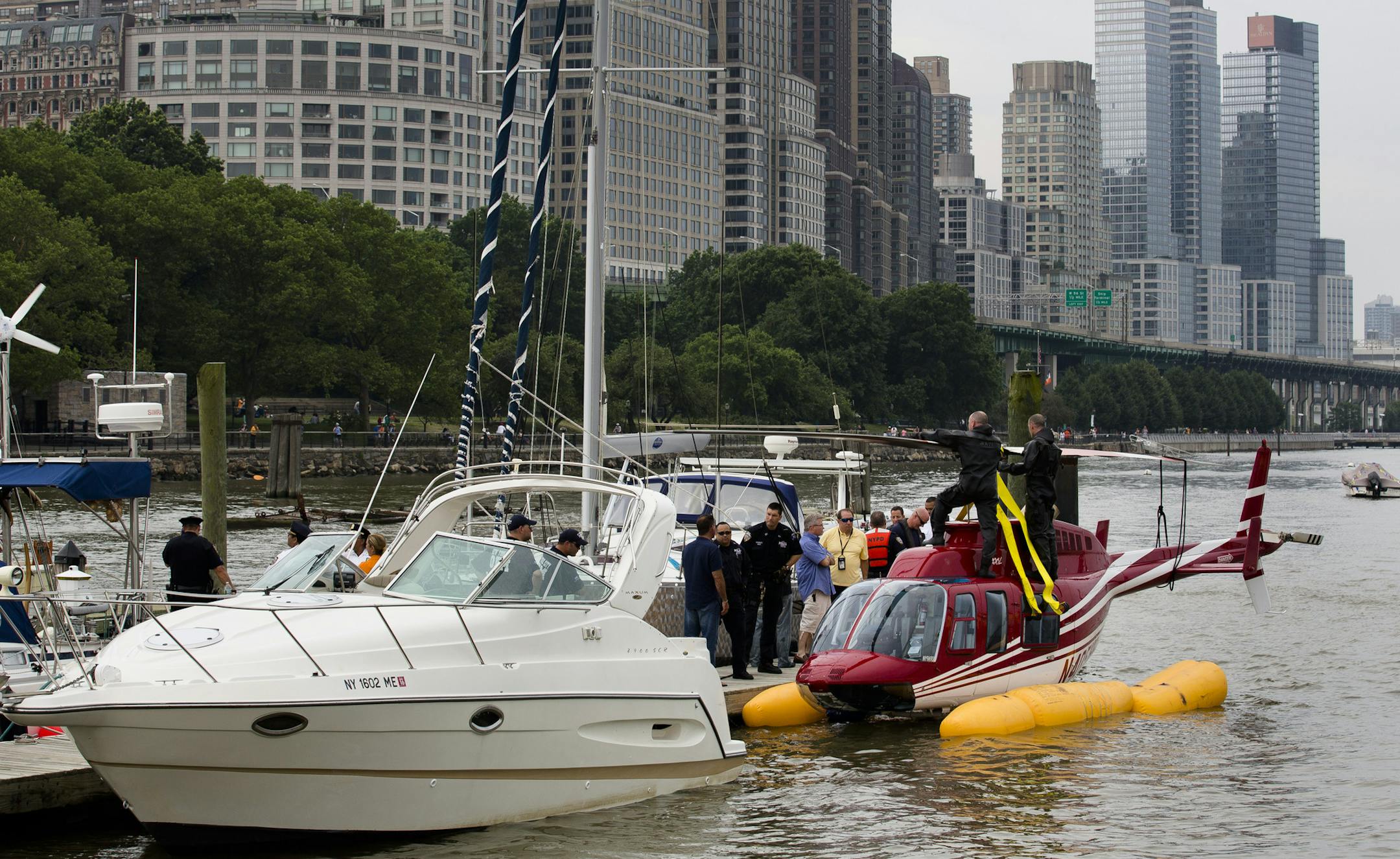 A helicopter rests on a pontoon at the 79th Street Boat Basin after emergency landing over the Hudson river, Sunday, June 30, 2013, in New York. New York authorities say a helicopter carrying four Swedish tourists landed in the Hudson River off Manhattan Sunday, but everyone has been rescued. (AP Photo/John Minchillo)