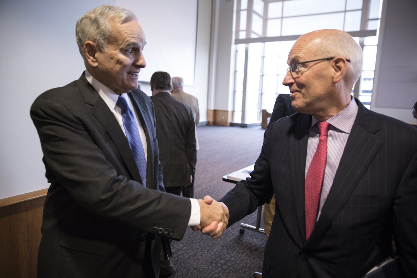 Minnesota Management and Budget commissioner Myron Frans, right, shakes hands with Governor Mark Dayton after the Minnesota Budget and Economic Forecast press conference.