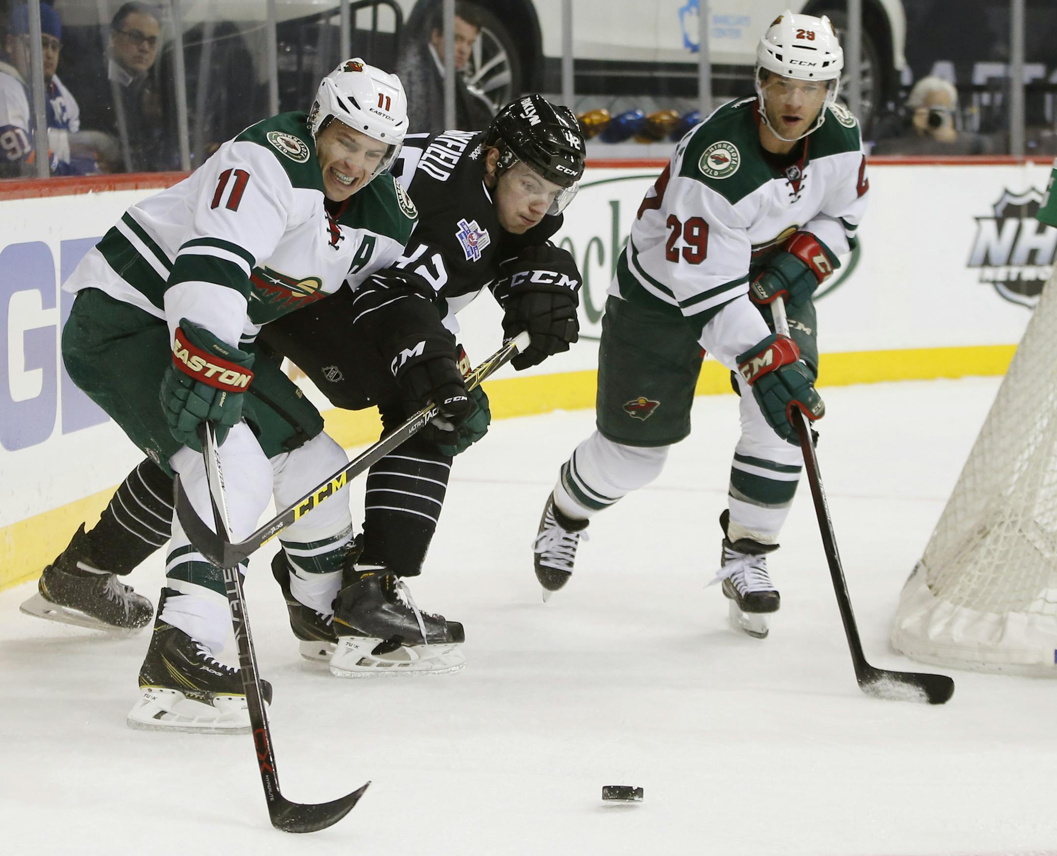 New York Islanders defenseman Scott Mayfield (42) defends Minnesota Wild left wing Zach Parise (11), who tries to get to the puck, as Wild right wing Jason Pominville (29) skates behind the net during the first period of an NHL hockey game in New York, Tuesday, Feb. 2, 2016. (AP Photo/Kathy Willens)