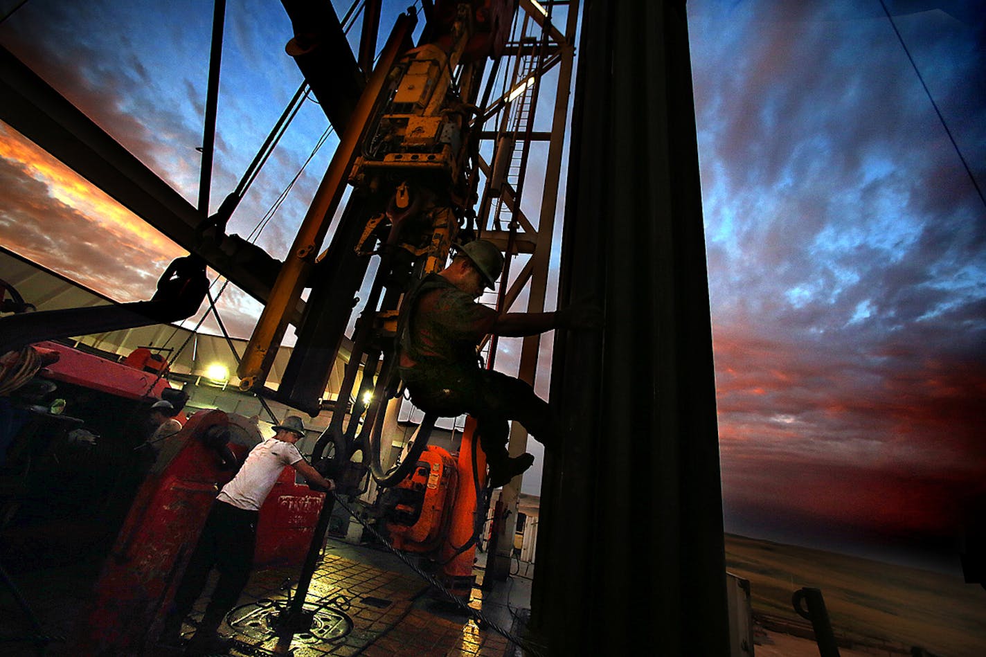 Derrick hand Scott Berreth (right) rappelled through the drilling rig structure as the crew prepared to restart machinery after some repairs had been made earlier in the morning. ] (JIM GEHRZ/STAR TRIBUNE) / December 17, 2013, Watford City, ND ‚Äì BACKGROUND INFORMATION- PHOTOS FOR USE IN FINAL PART OF NORTH DAKOTA OIL BOOM PROJECT: Men work around the clock at Raven Rig No. 1 near Watford City, one of nearly 200 towering oil rigs in the Bakken. Once the rigs drill holes, several miles deep and