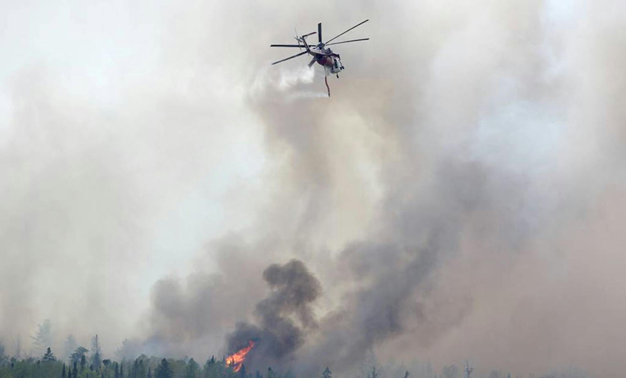 A helicopter drops water over a forest fire near Ely, Minn., Thursday.