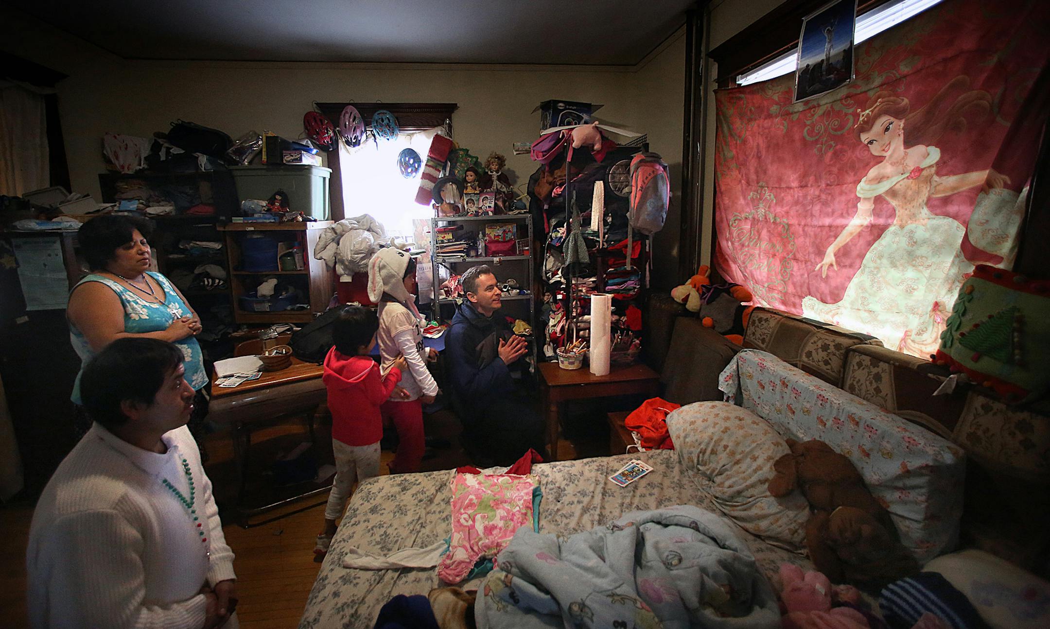Fr. Joseph Williams led Sucel Dalia Onofre Soriano (second from left), two of her children, Angela, 9 (hat), and Marlen, 10 in prayer at their home near St. Stephen&#x221a;&#xef;s. At left is and Jorge Matute, who was in the group from St. Stephen&#x221a;&#xef;s with Fr. Joseph. ] (JIM GEHRZ/STAR TRIBUNE) / March 24, 2013 / 9:00 AM Minneapolis, MN &#x221a;&#xea; BACKGROUND INFORMATION- St. Stephen&#x221a;&#xef;s Church in south Minneapolis is in the midst of a &#x221a;&#xed;rebirth,&#x221a;&#xec