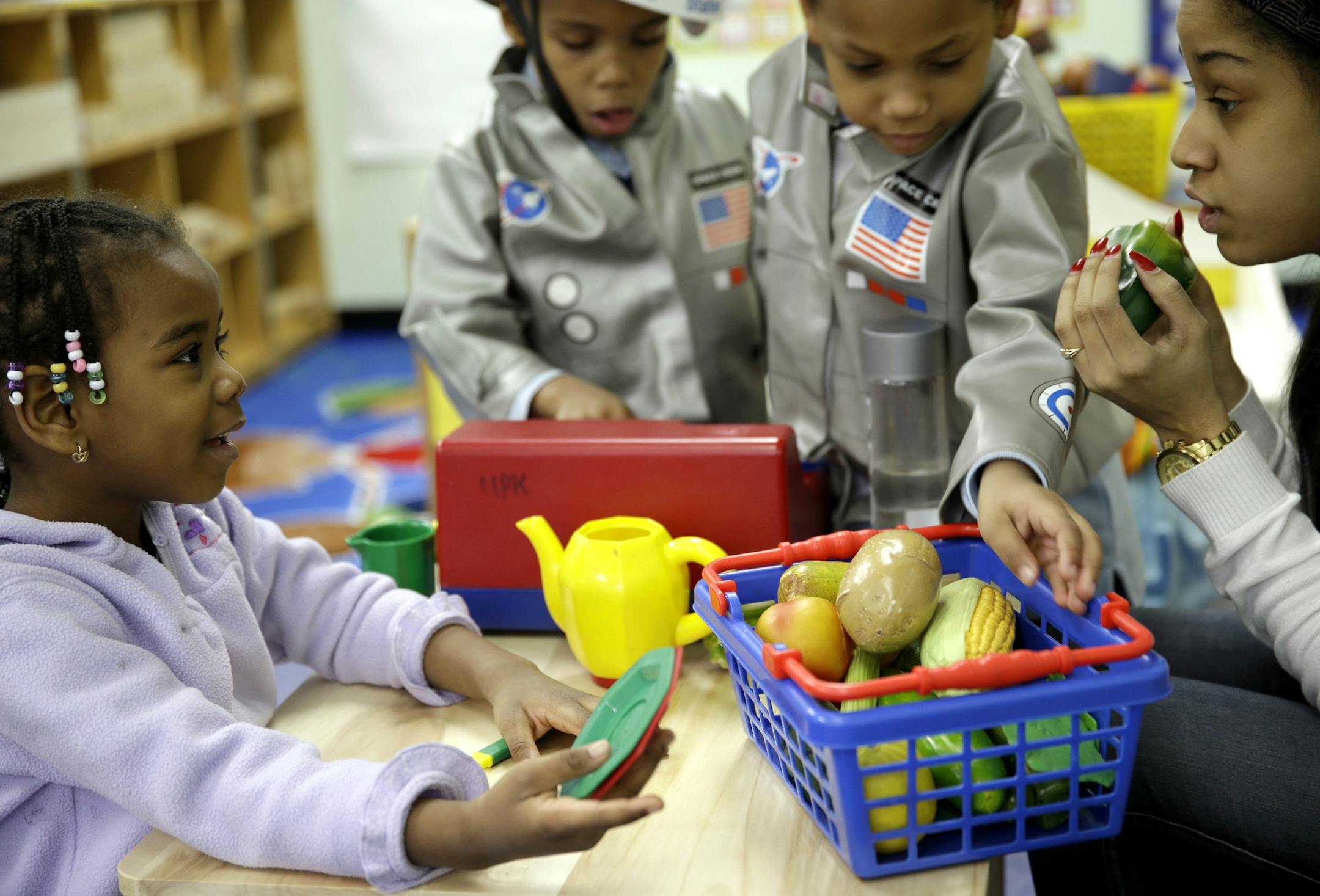In this Tuesday, Jan. 21, 2014 photo, Oumou Balde, 4, left, plays with her teacher Jacqualine Sanchez, right, and some pretend food in a pre-kindergarten class at the Sheltering Arms Learning Center in New York. Balde participated in a program that was produced in conjunction with Sesame Street to educate children about nutrition and health. (AP Photo/Seth Wenig)