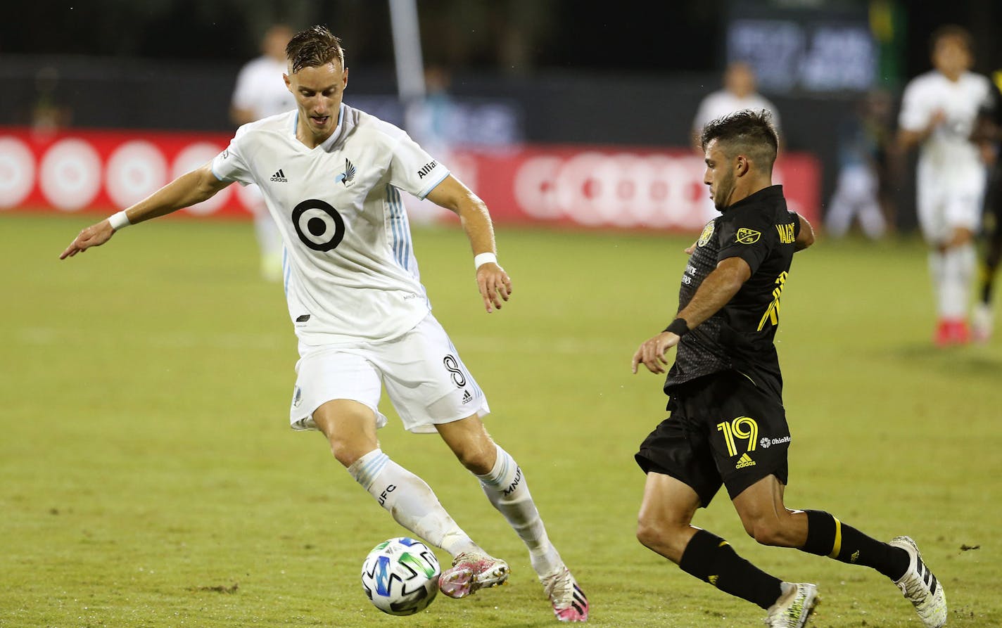 Columbus Crew defender Milton Valenzuela (19) closes in on Minnesota United midfielder Jan Gregus (8) during the second half of an MLS soccer match in Kissimmee, Fla., Tuesday, July 28, 2020. (AP Photo/Reinhold Matay)