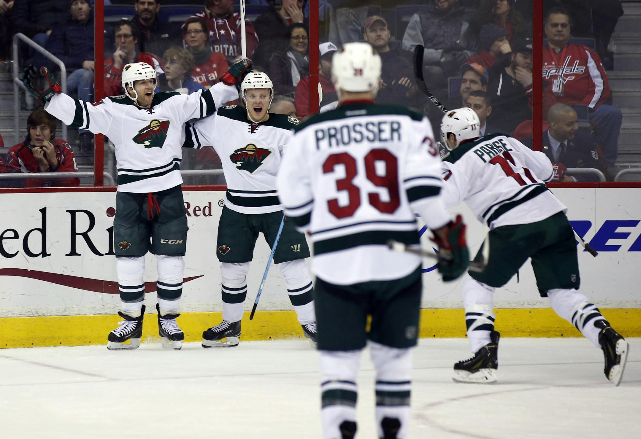 Minnesota Wild right wing Jason Pominville, left, celebrates his goal with center Mikael Granlund (64), from Finland, as defenseman Nate Prosser (39) and left wing Zach Parise (11) come to join, during the third period of an NHL hockey game against the Washington Capitals, Thursday, March 5, 2015, in Washington. The Wild won 2-1. (AP Photo/Alex Brandon)