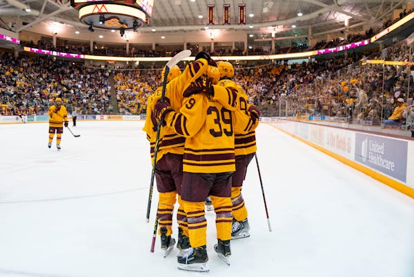 Minnesota players swarm forward Matthew Knies (89) to celebrate after he scored a goal in the second period against the University of Minnesota Duluth