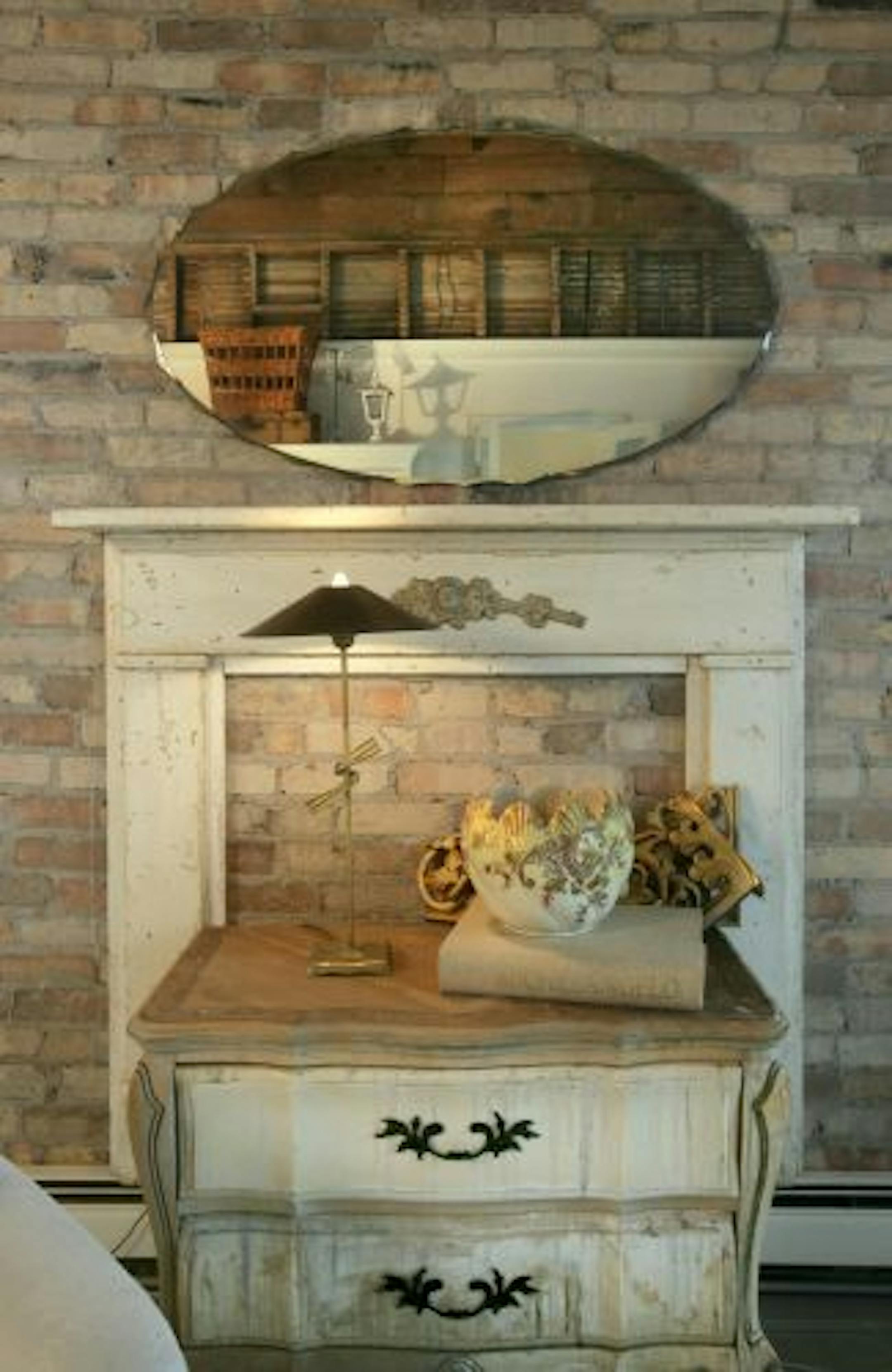 Exposed brick in the living room provides a backdrop for a mantle built from salvaged pieces and a second-hand bombe chest with a waxed maple top.