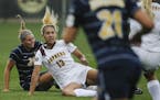 Gophers women's soccer player Taylor Stainbrook (13) loses her footing, but not before passing to teammate Sydney Squires during the University of Min