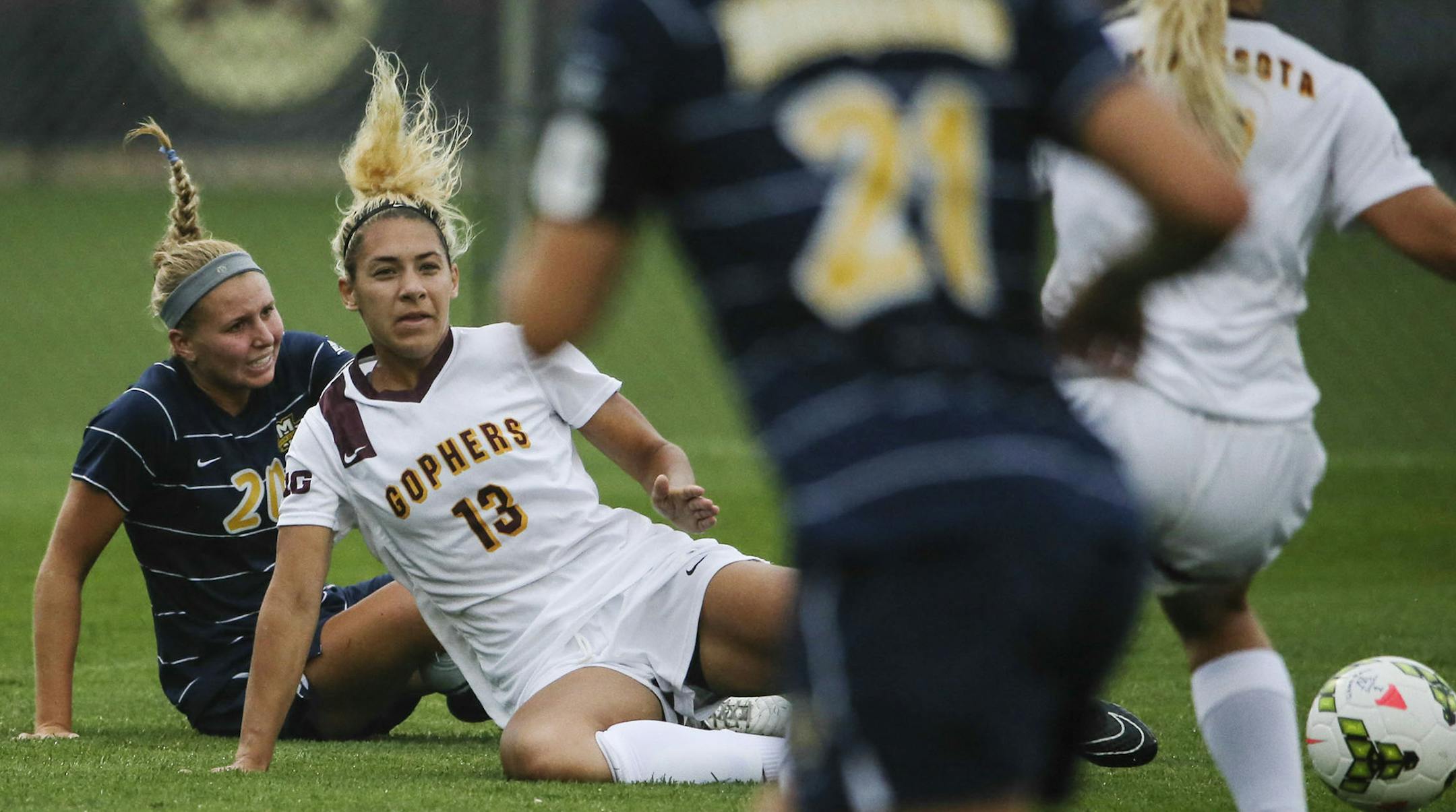 Gophers women's soccer player Taylor Stainbrook (13) loses her footing, but not before passing to teammate Sydney Squires during the University of Minnesota's game with Marquette University at Elizabeth Lyle Robbie Stadium Friday Aug. 29, 2014, in St. Paul, MN.] (DAVID JOLES/STARTRIBUNE)djoles@startribune.com Gophers vs. Marquette in women's soccer. Gophers women's soccer feature on Simone Kolander. She was Big Ten offensive player of the week for the first week of the season: tallying nine poin