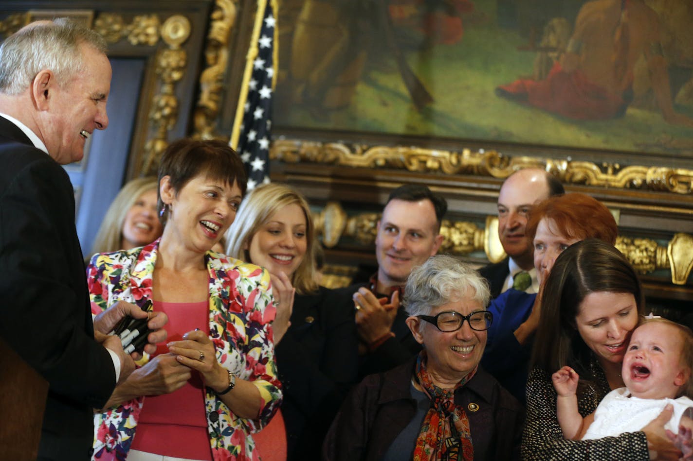 Gov. Mark Dayton, who signed the Women's Economic Security Act into law on Sunday, got a kick of Sen. Katie Sieben's crying one-year old daughter, Greta, who got upset after Sen. Sandra Pappas, second from left, picked her up high in the air. In the middle is Rep. Phillys Kahn.