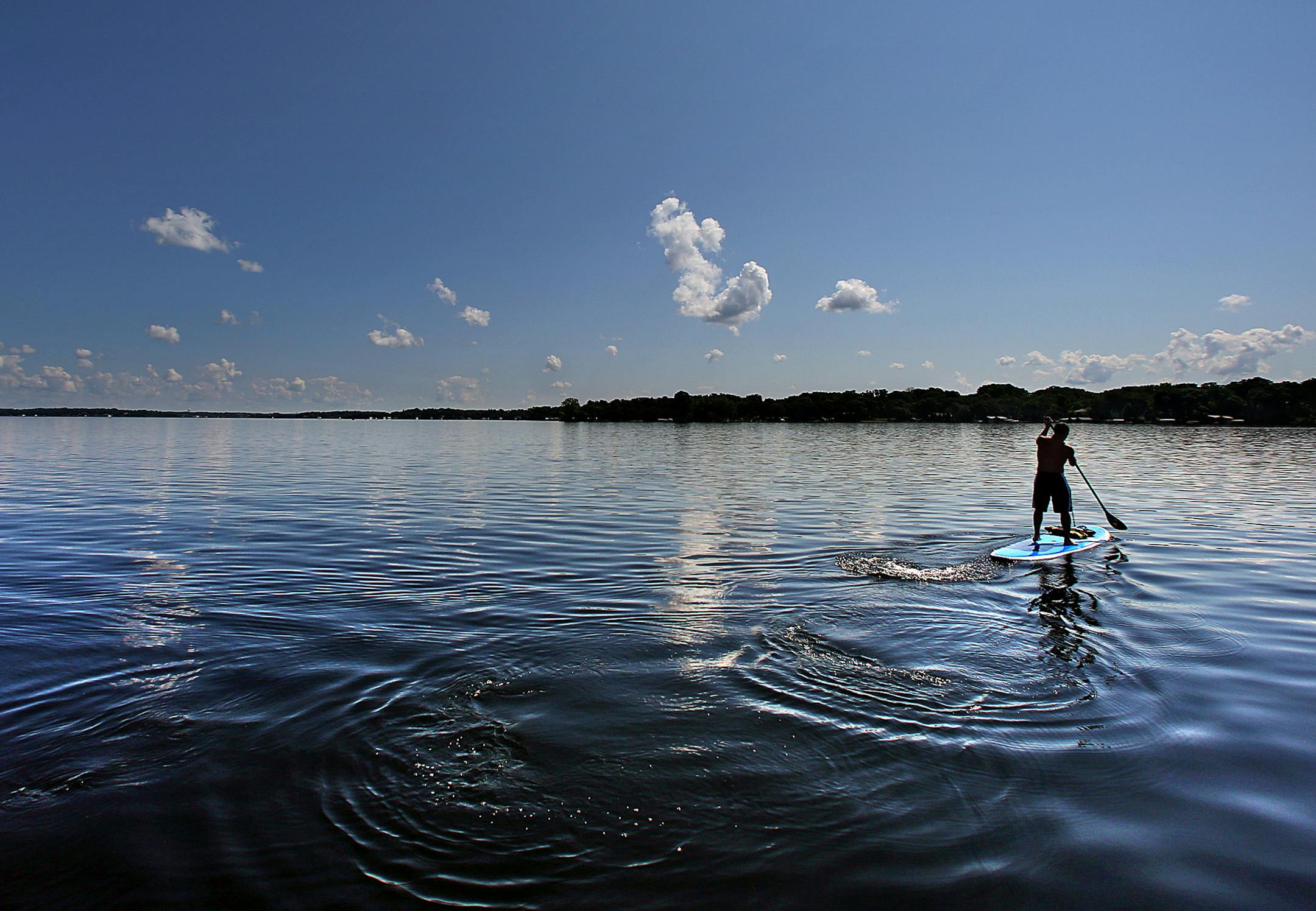 A man used a paddle board to cross an unusually serene Lake Minnetonka. ]JIM GEHRZ ‚Ä¢ jgehrz@startribune.com / Minneapolis, MN / July 3, 2014 / 11:00 AM / BACKGROUND INFORMATION: The July 4th weekend is usually the busiest weekend of the entire year for Lake Minnetonka and other Minnesota waterways. But not this year. Record flooding has forced unprecedented wake restrictions on lakes like Minnetonka, turning a usually raucous, crowded lake of jet-skiers, boats and cruises into