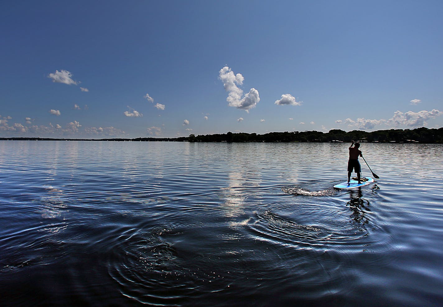 A man used a paddle board to cross an unusually serene Lake Minnetonka. ]JIM GEHRZ &#x201a;&#xc4;&#xa2; jgehrz@startribune.com / Minneapolis, MN / July 3, 2014 / 11:00 AM / BACKGROUND INFORMATION: The July 4th weekend is usually the busiest weekend of the entire year for Lake Minnetonka and other Minnesota waterways. But not this year. Record flooding has forced unprecedented wake restrictions on lakes like Minnetonka, turning a usually raucous, crowded lake of jet-skiers, boats and cruises into