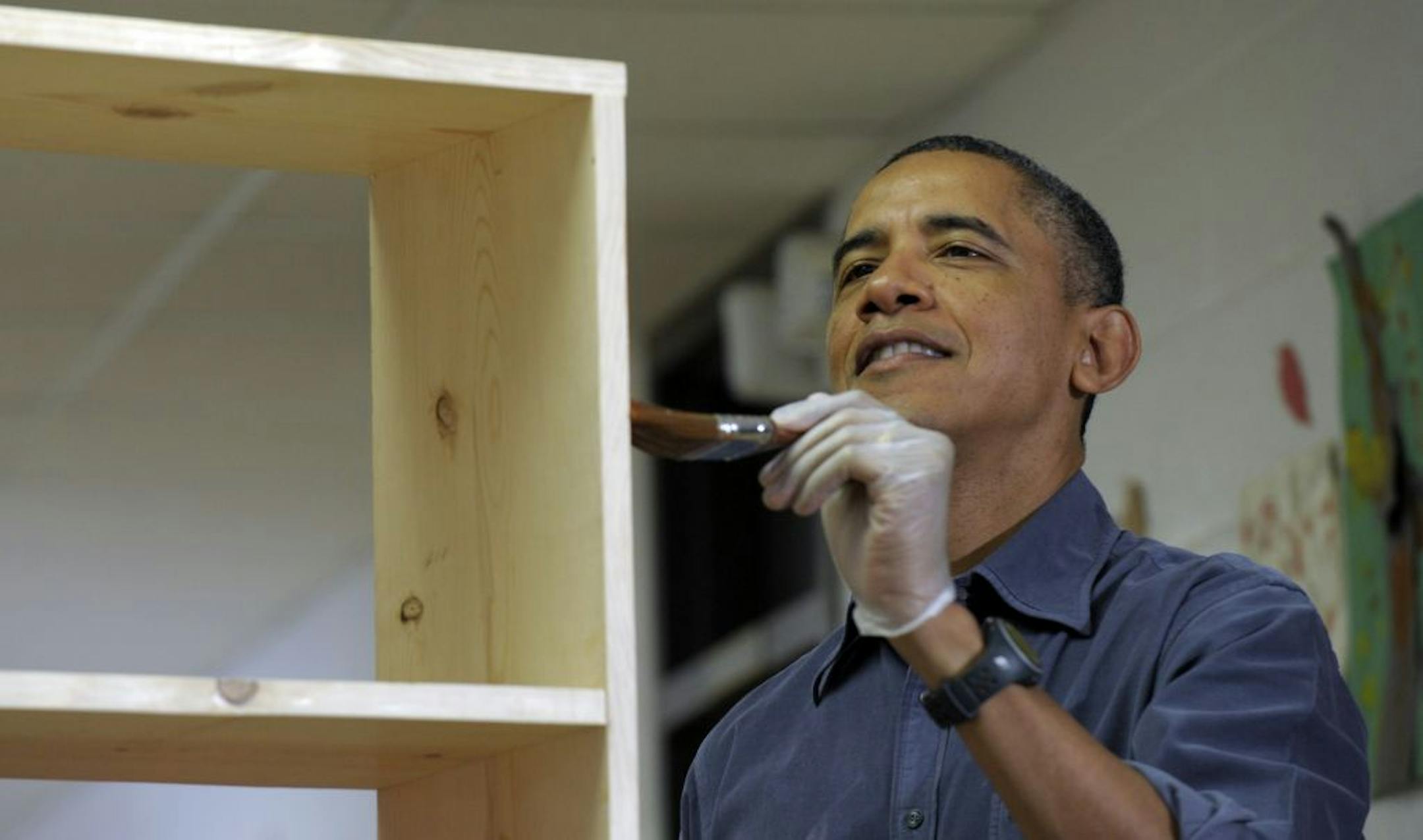 President Barack Obama stains a bookshelf at Burrville Elementary School in Washington, Saturday, Jan. 19, 2013, as the first family participated in a community service project for the National Day of Service, part of the 57th Presidential Inauguration.
