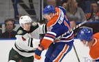 Minnesota Wild's Mike Reilly, left, and Edmonton Oilers' Rob Klinkhammer battle for the puck during the first period of an NHL preseason hockey game S