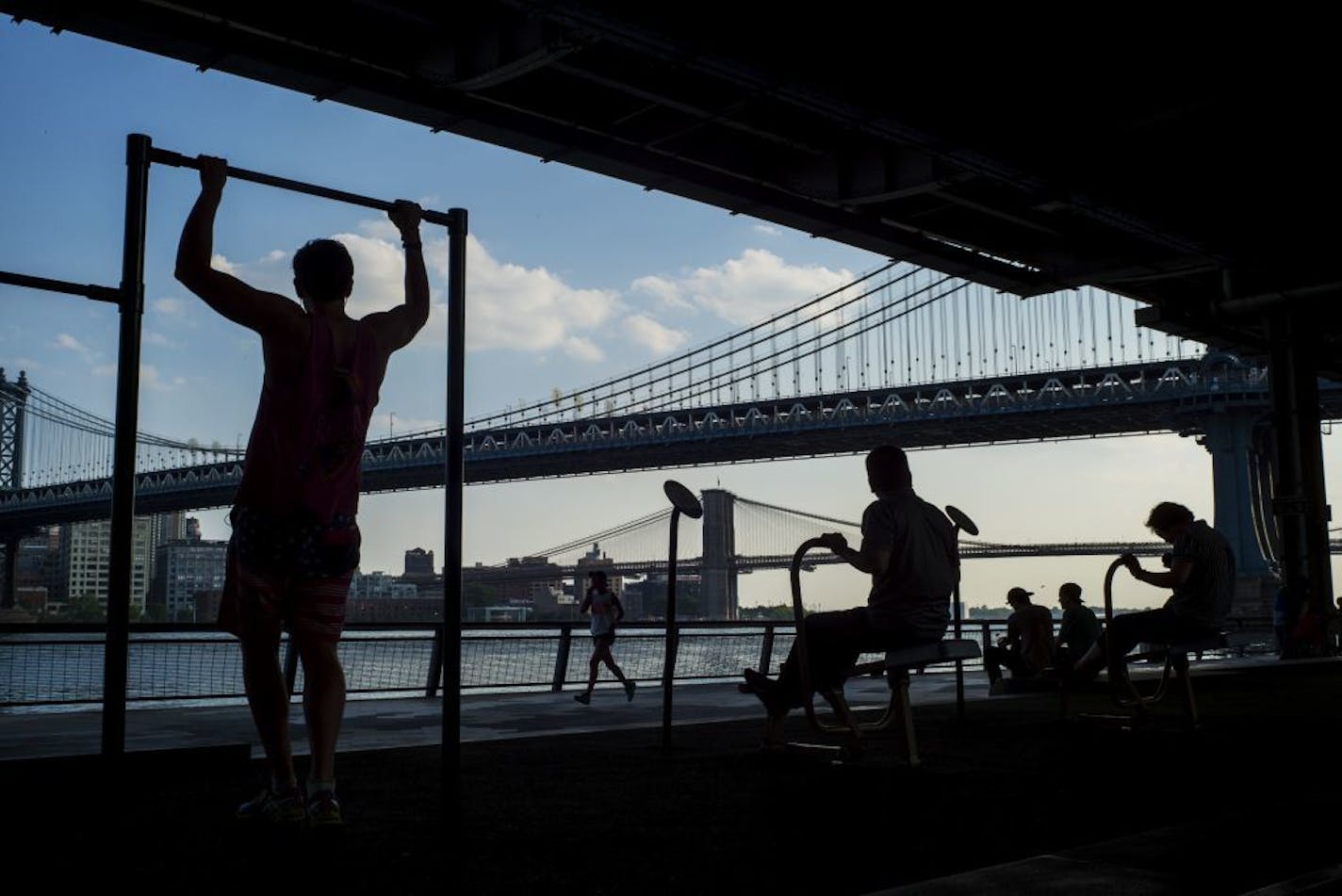 FILE -- People exercise at a public park along the East River on Manhattan's Lower East Side, June 10, 2015. A new analysis of data from more than 55,000 people finds that by not smoking, and by exercising moderately and eating a healthy diet, it is possible to tamp down even the worst genetic risk for heart disease.