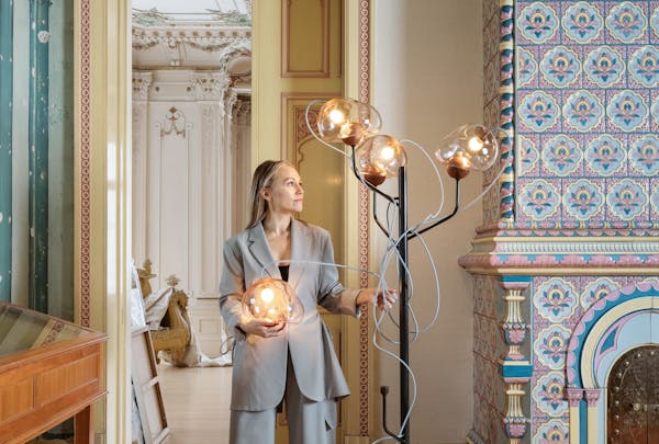 Designer Victoria Sass stands with light fixtures from the Ontologia Collection at the American Swedish Institute.