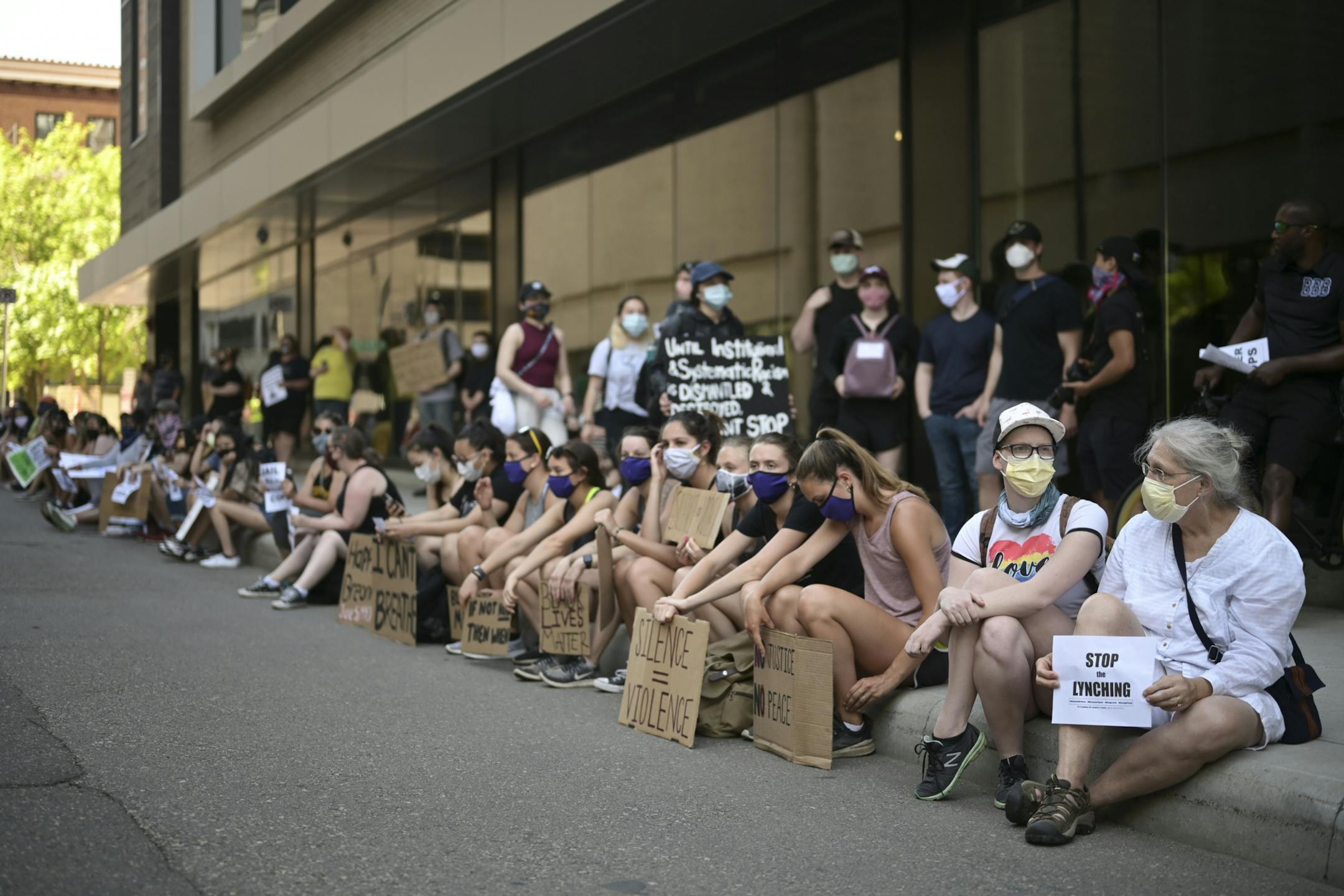 Dozens of demonstrators sat on the curb across from Attorney General Keith Ellison's downtown St. Paul office Friday.