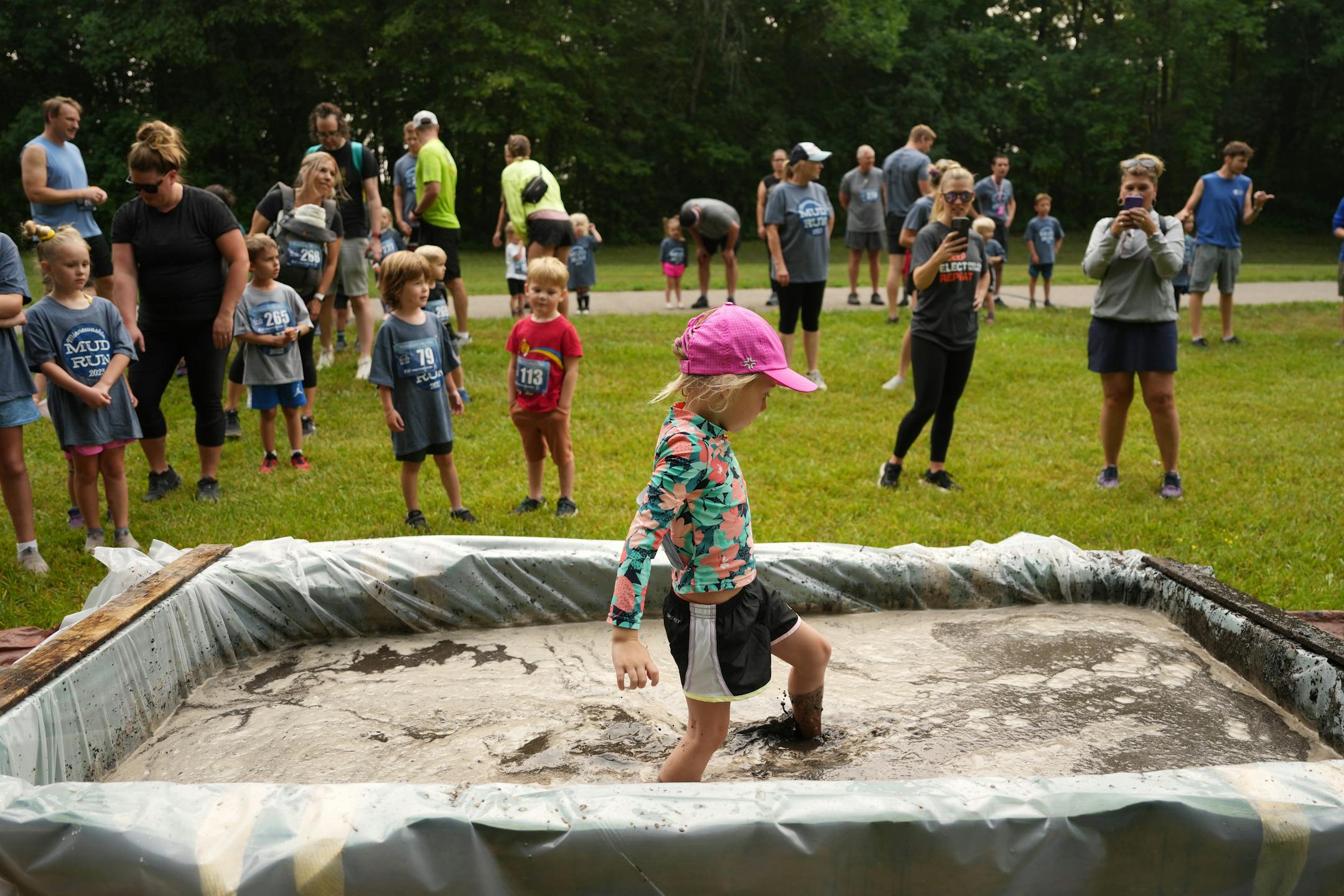 A group of children, who admittedly had been told their whole young lives not to play in mud said a parent on scene, watch skeptically as Willa Gasow, 5, of Chanhassen wades through a mud pit during the Minneswashta Mud Run's Mini Mud Run.